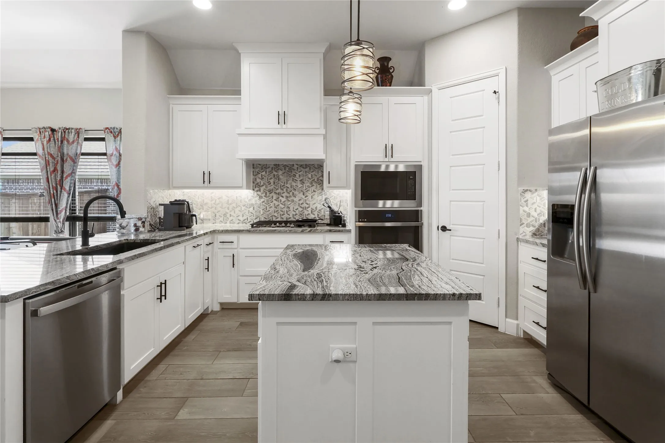 White cabinetry, stainless steel appliances, wood-finish flooring, a kitchen island, and recessed lighting