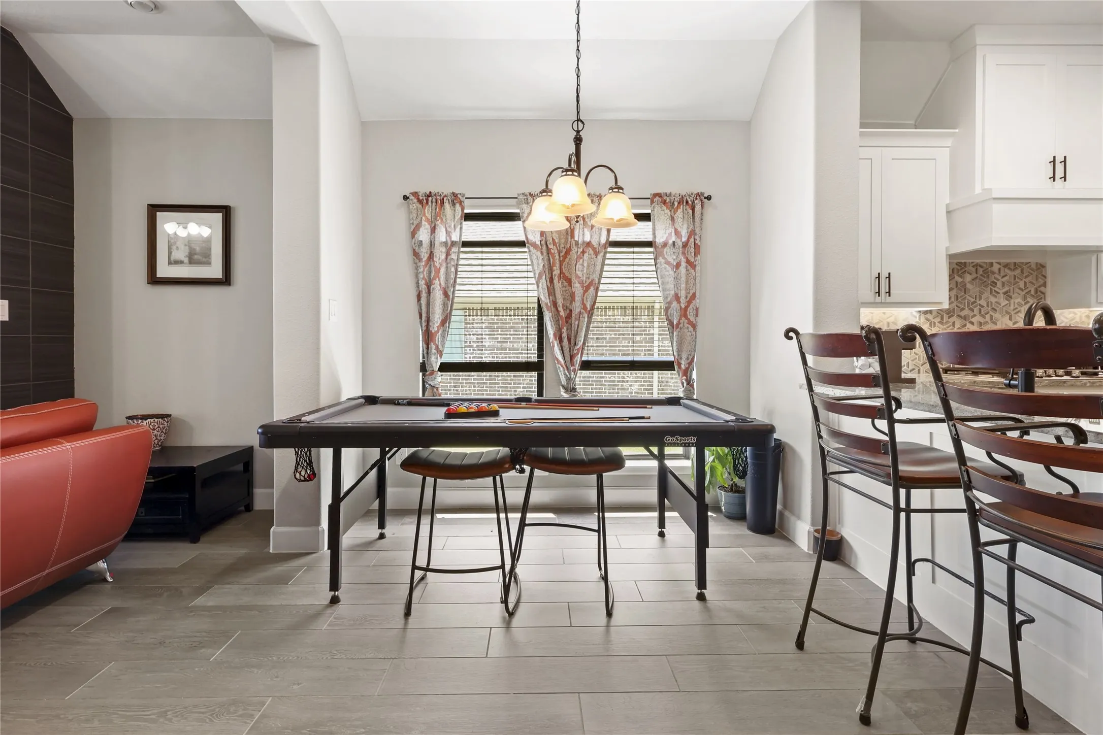 Recessed lighting, wood-finish flooring, white cabinetry with dark hardware, a tile backsplash, and a decorative pendant light fixture