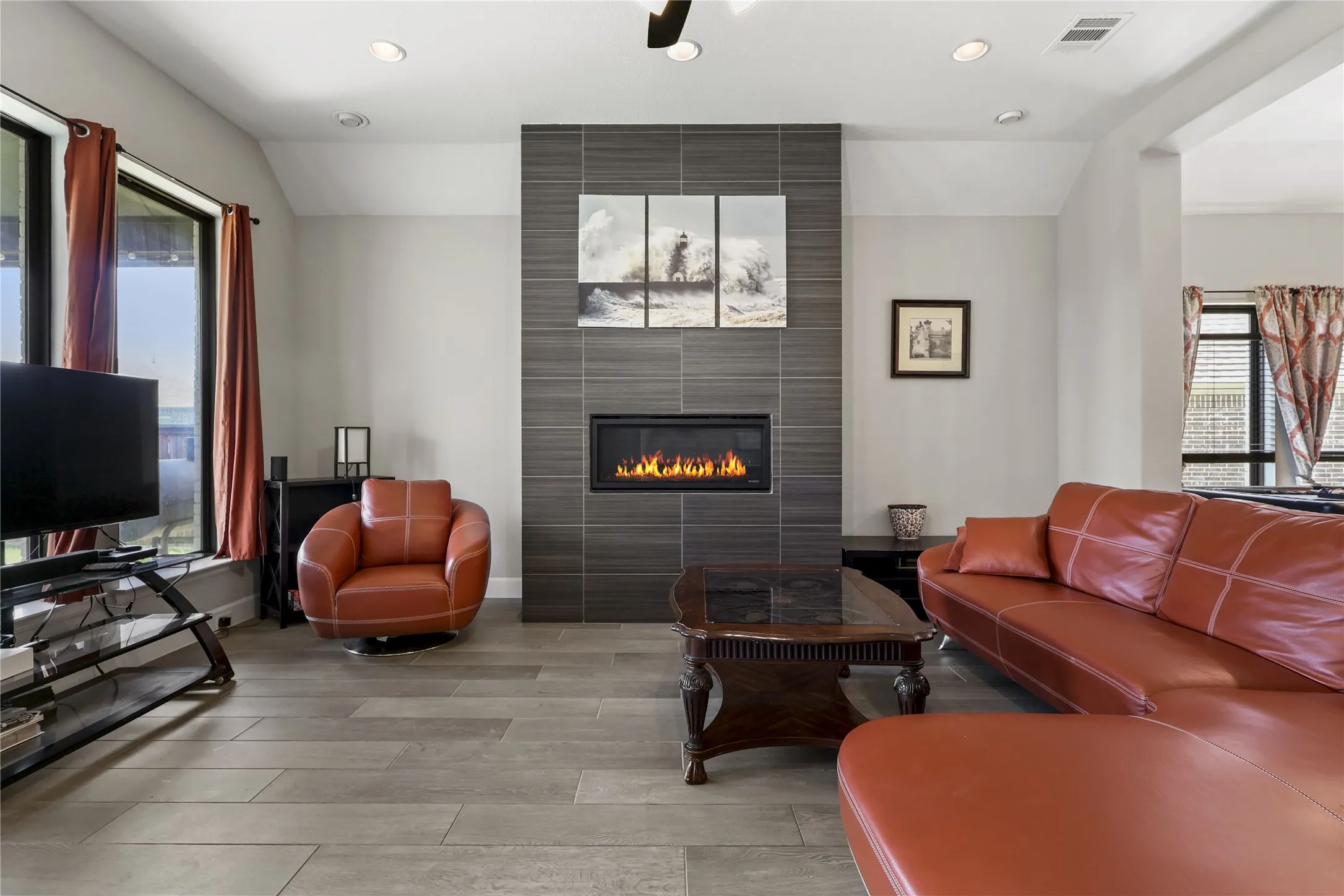 Living area featuring a floor-to-ceiling tile fireplace surround, rectangular fireplace insert, wood-finish flooring, and recessed lighting