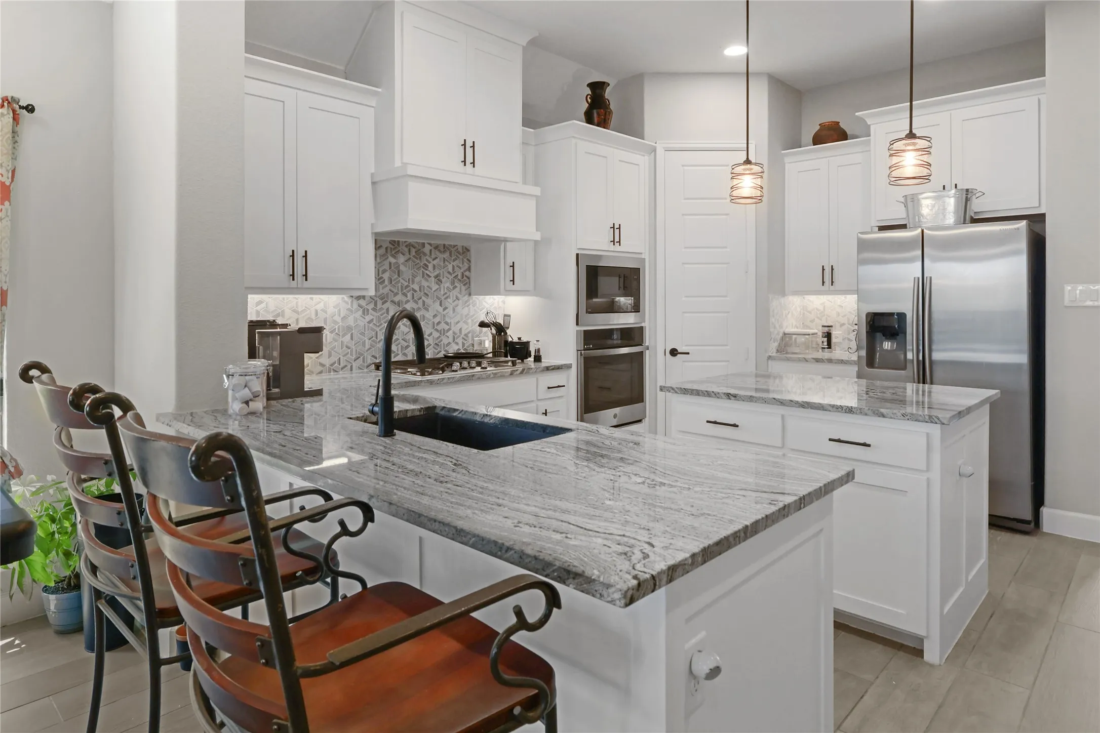 Kitchen featuring white cabinetry, light-toned countertops, a built-in oven and microwave, a gas cooktop, and contemporary pendant lighting