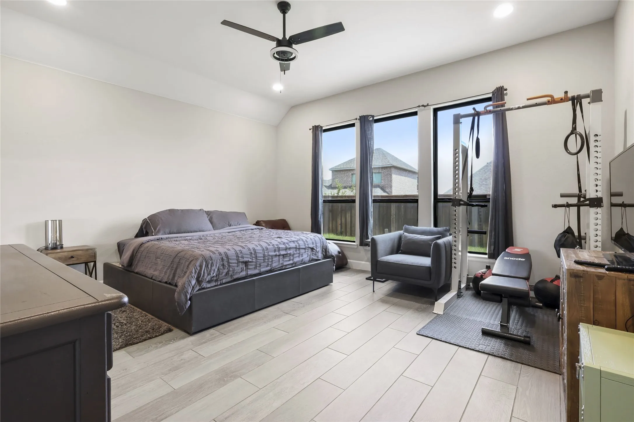Recessed lighting, light-toned tile flooring, three large windows, and a ceiling fan with integrated lighting