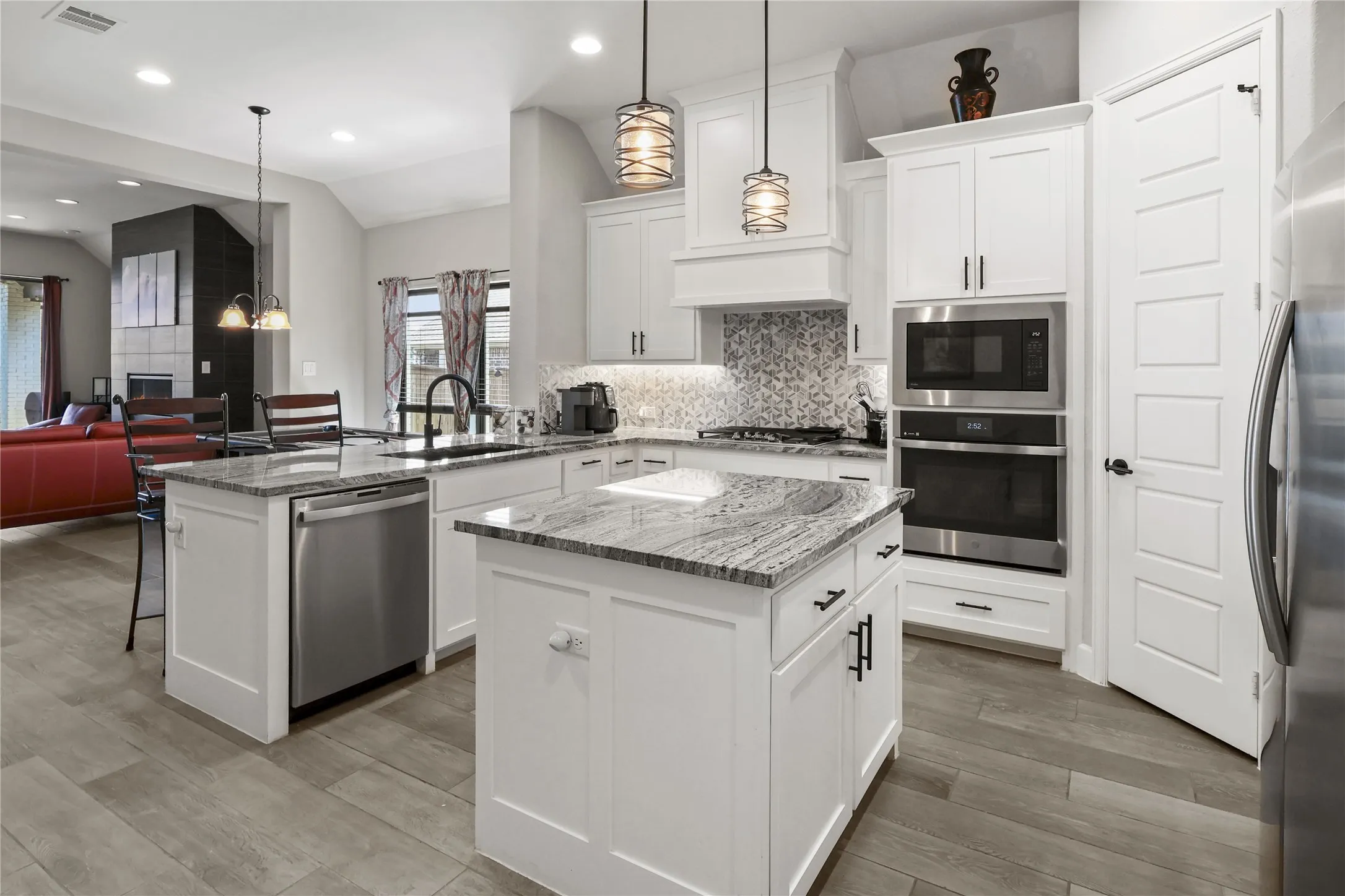 Kitchen featuring two islands, stainless steel appliances, white cabinetry, and wood-finish flooring