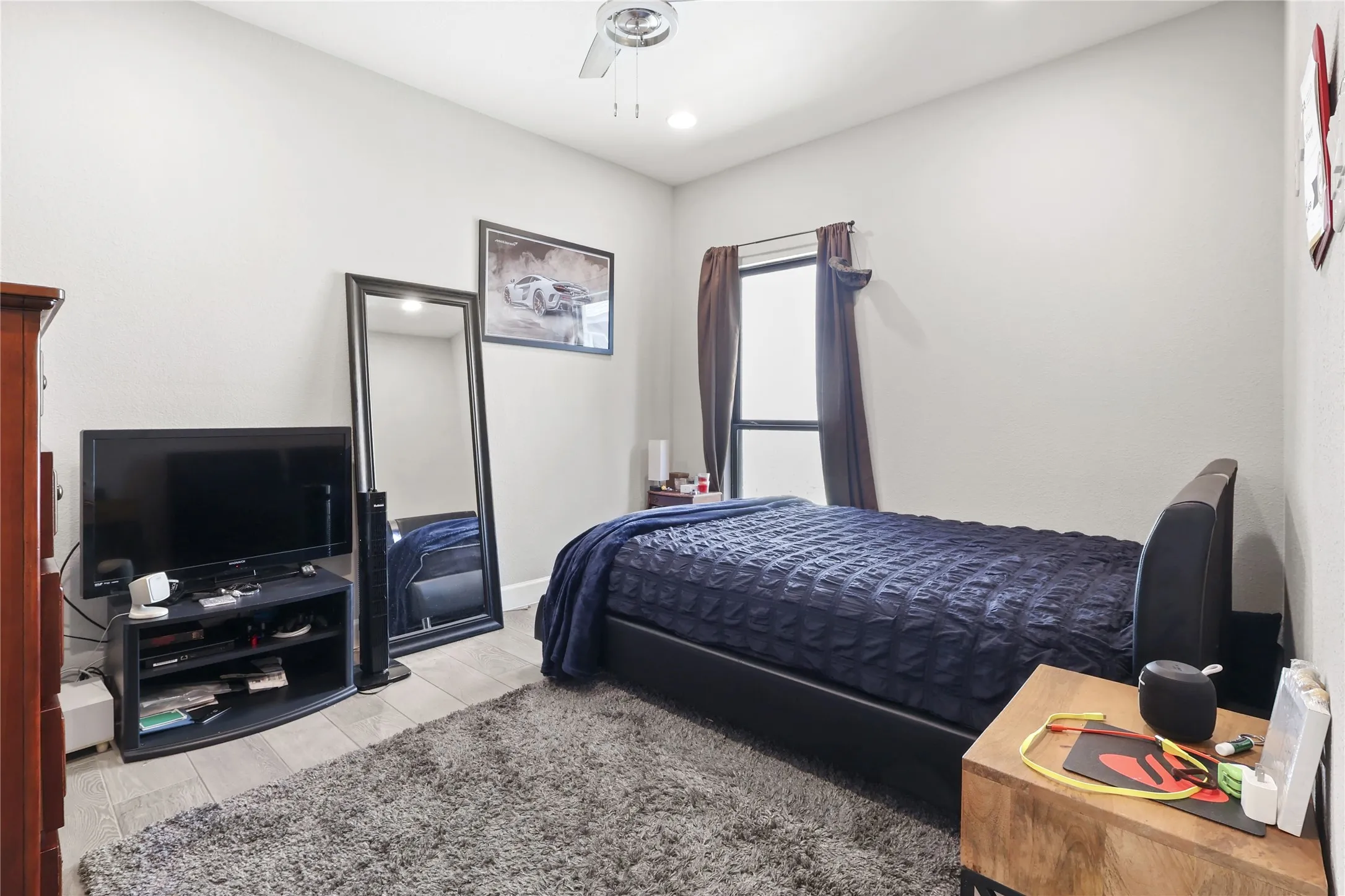 Recessed lighting, ceiling fan, wood-finish flooring, and a single window with curtain rod