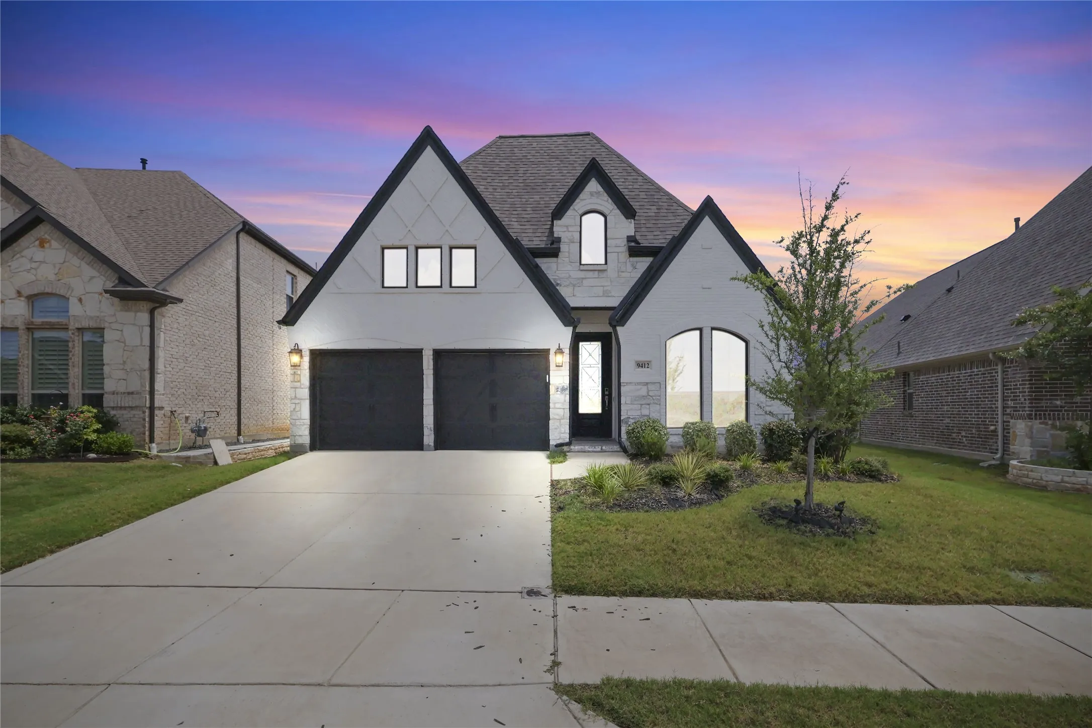 Contemporary exterior with a prominent gabled roofline, stone and stucco facade, an attached two-car garage, and a concrete driveway