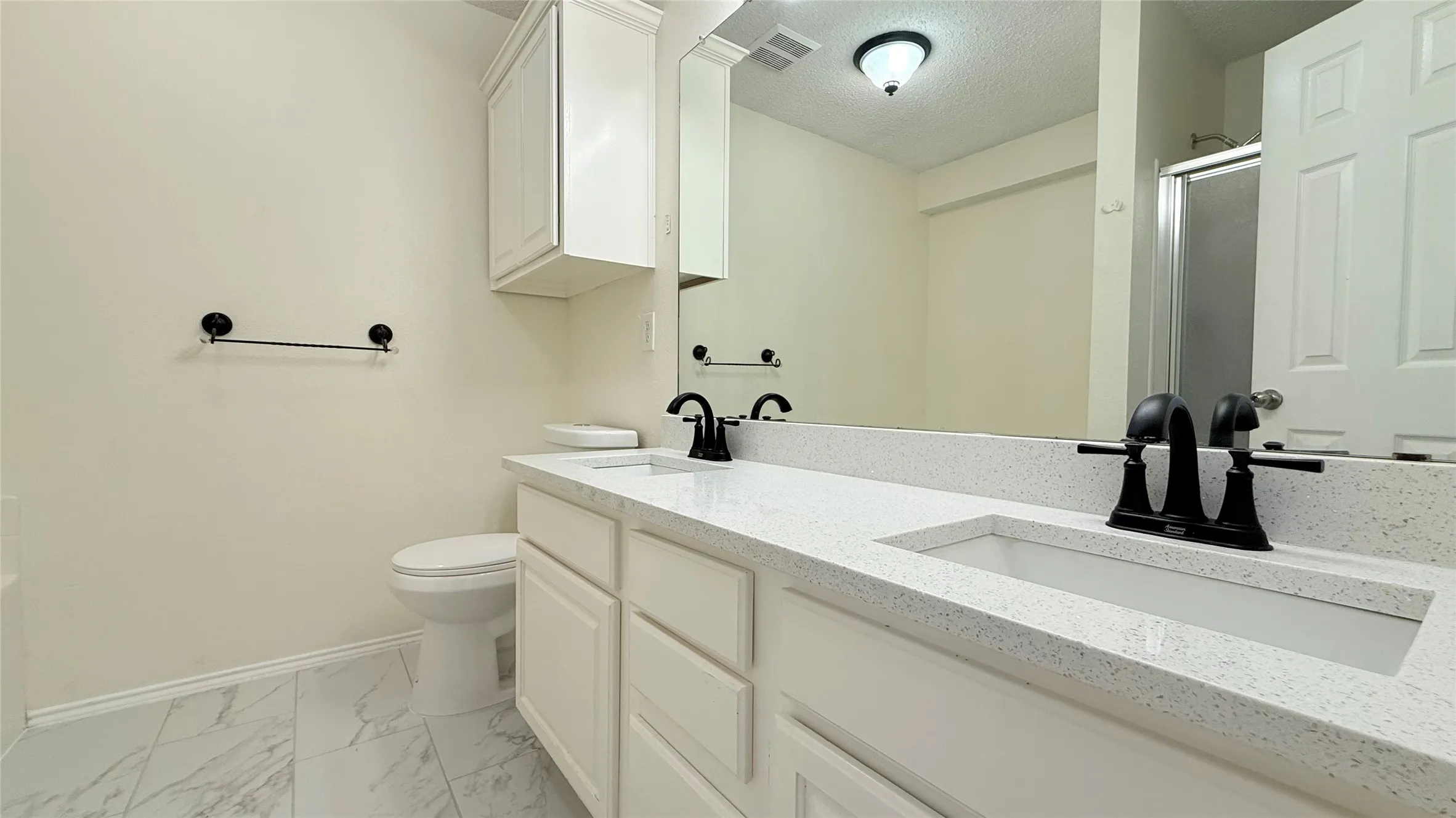 Double vanity with integrated sinks, white cabinetry, quartz countertops, and matte black fixtures