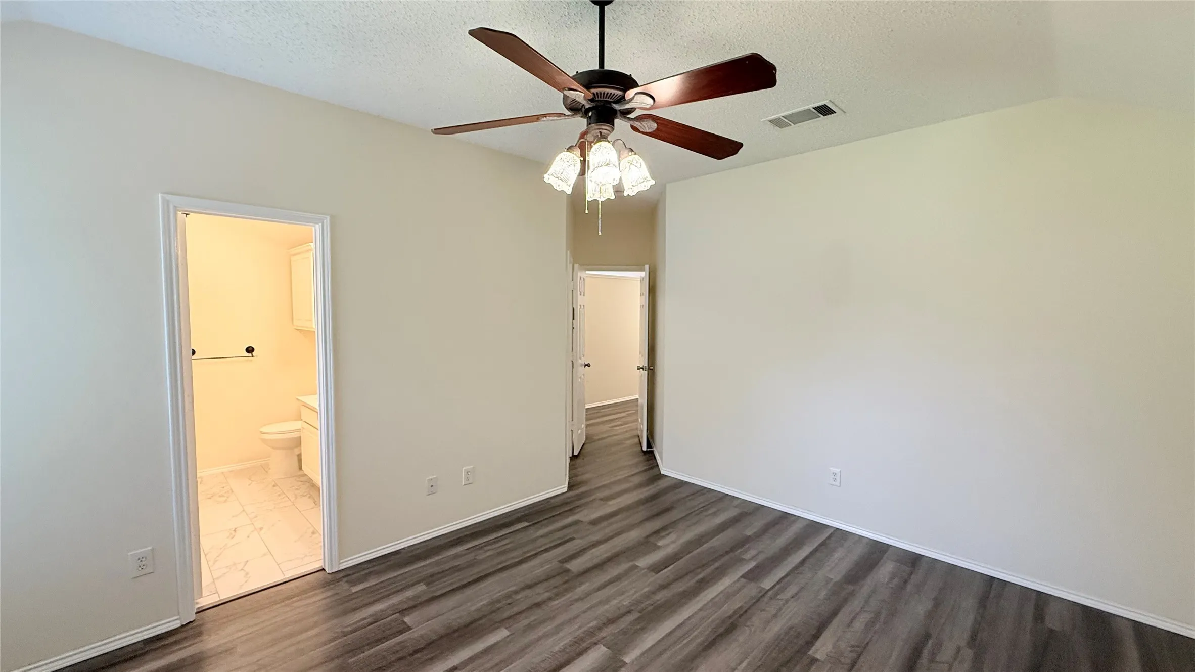 Vaulted ceiling with a ceiling fan, wood-finish flooring, and light-toned walls