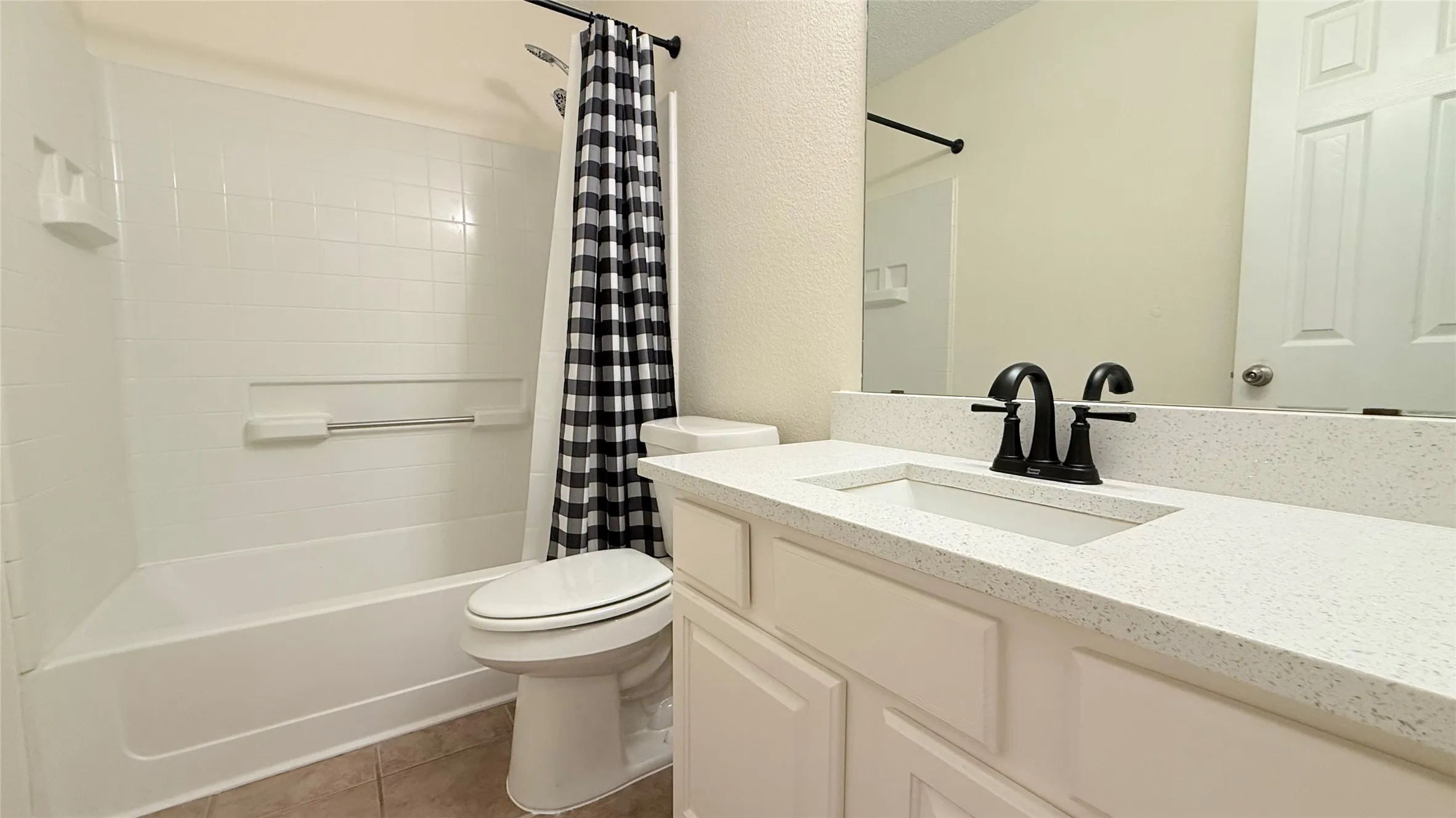 Bathroom featuring a single-basin vanity with a light-colored countertop and a black-finish faucet