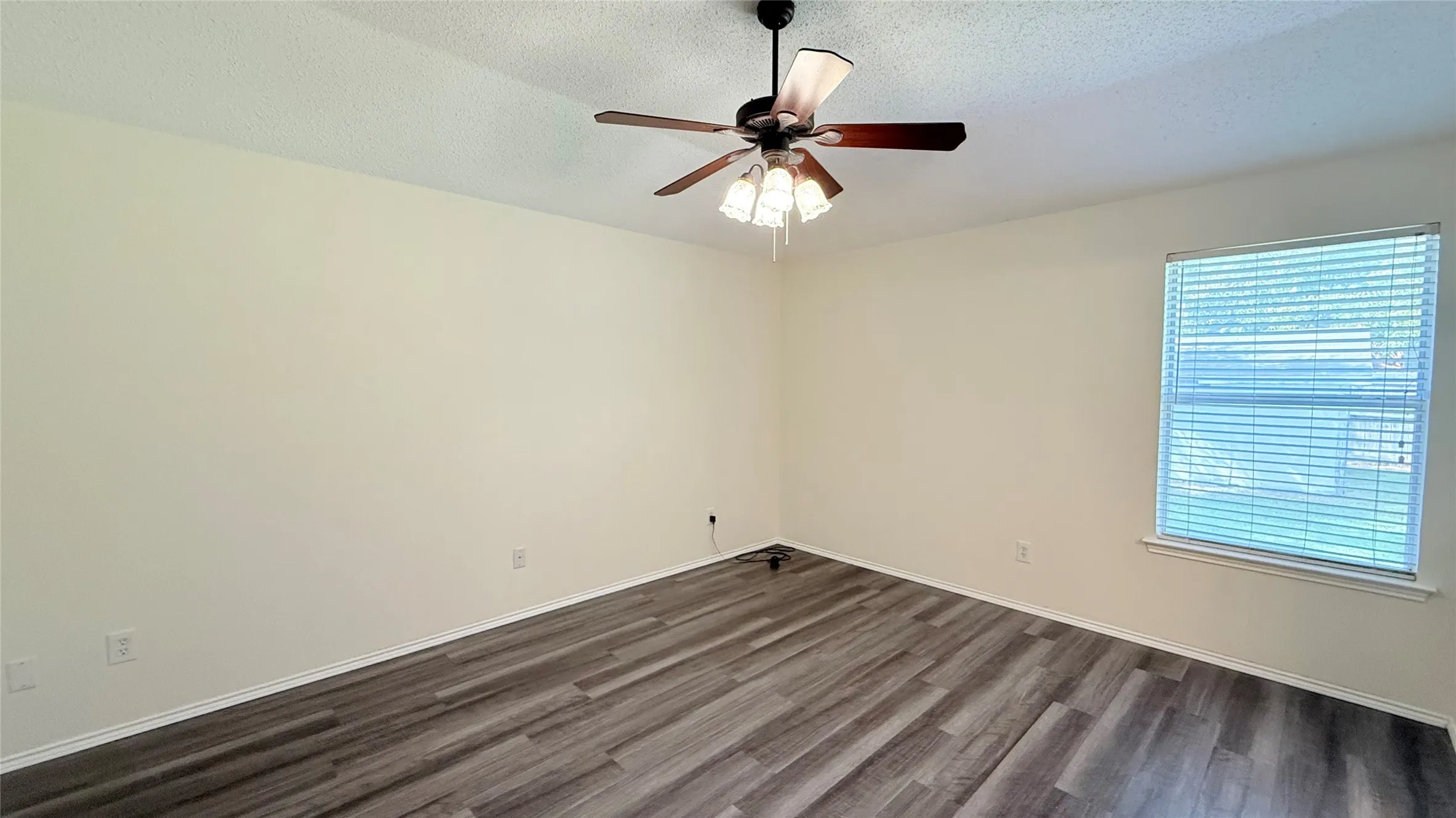 Wood-finish flooring, ceiling fan with light fixture, window with blinds, and light-toned walls
