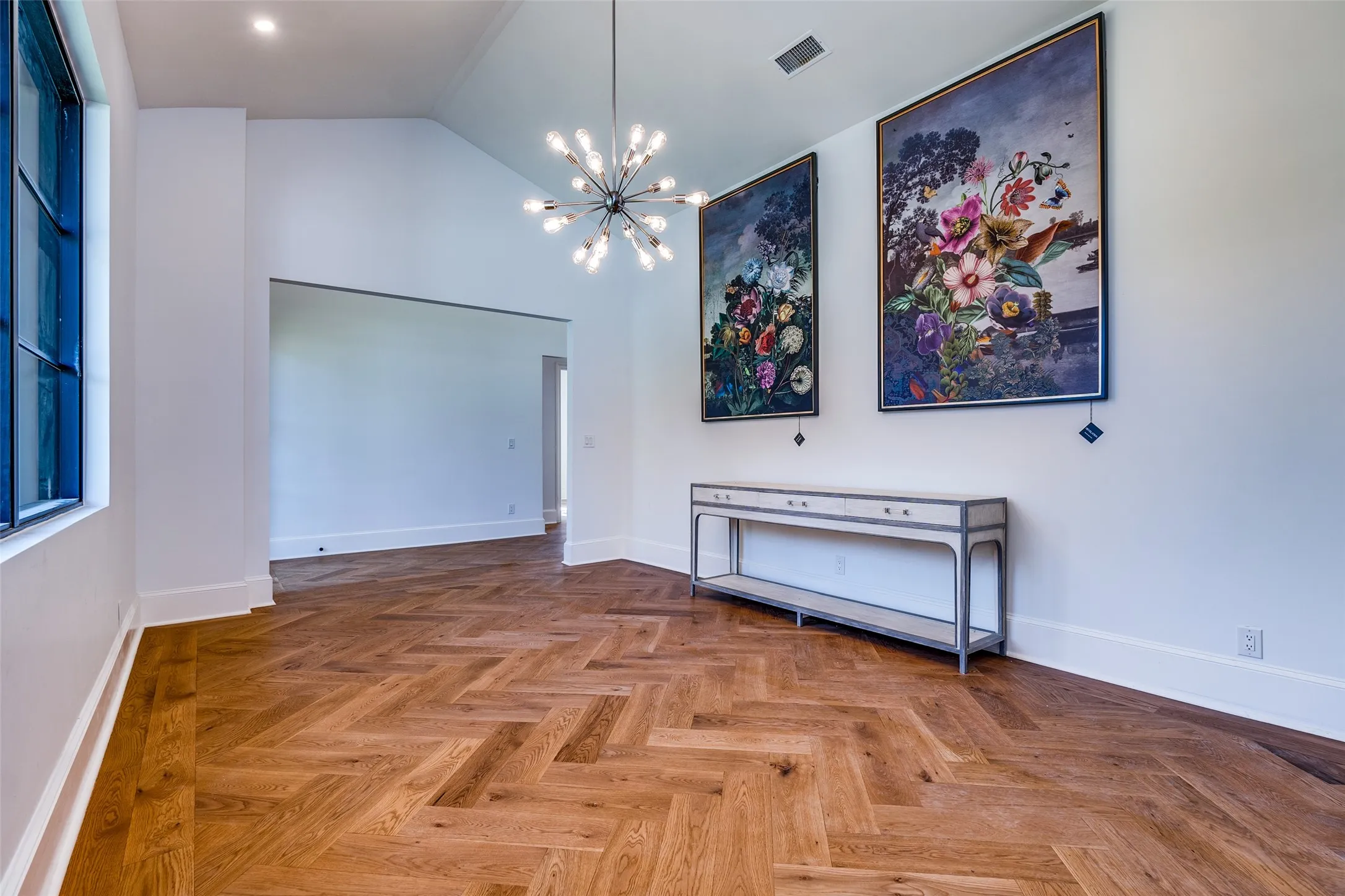 Herringbone wood-finish flooring, vaulted ceiling, recessed lighting, and a modern chandelier