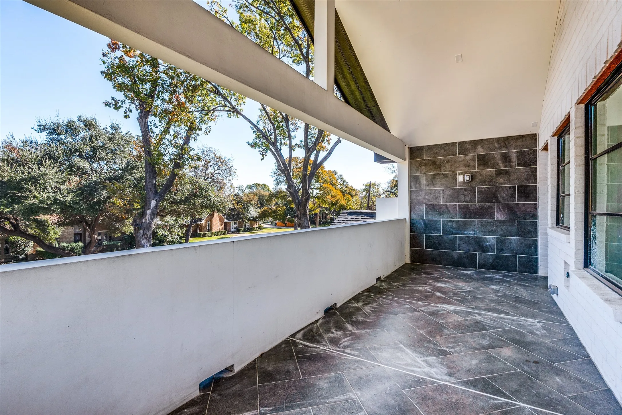 Covered balcony featuring tile flooring and a textured accent wall
