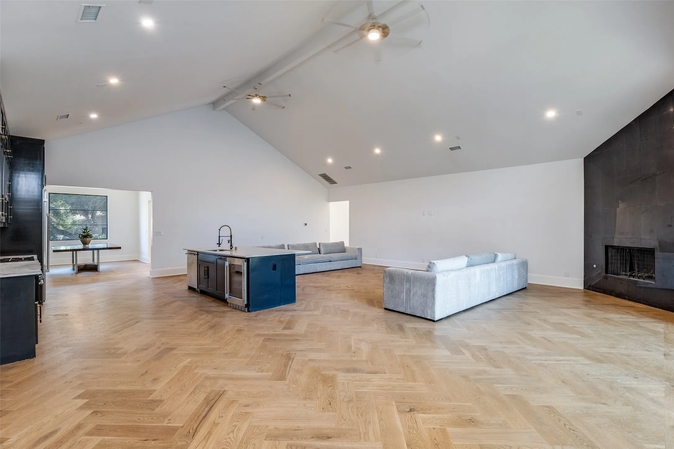 Spacious interior featuring a vaulted ceiling, recessed lighting, and a prominent dark-toned fireplace wall