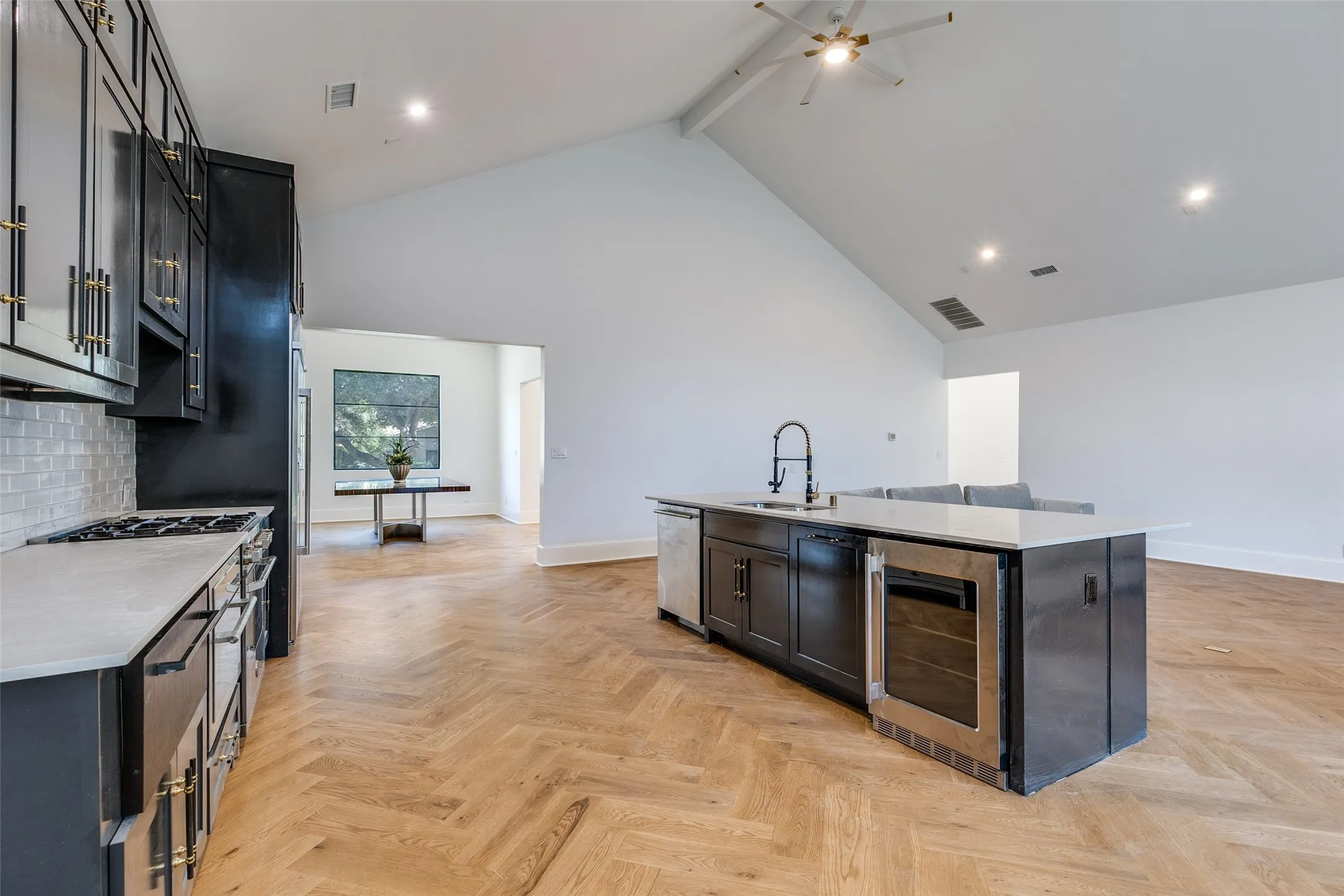 Kitchen featuring dark cabinetry with gold-finish hardware, stainless steel appliances, a tile backsplash, and light-tone countertops