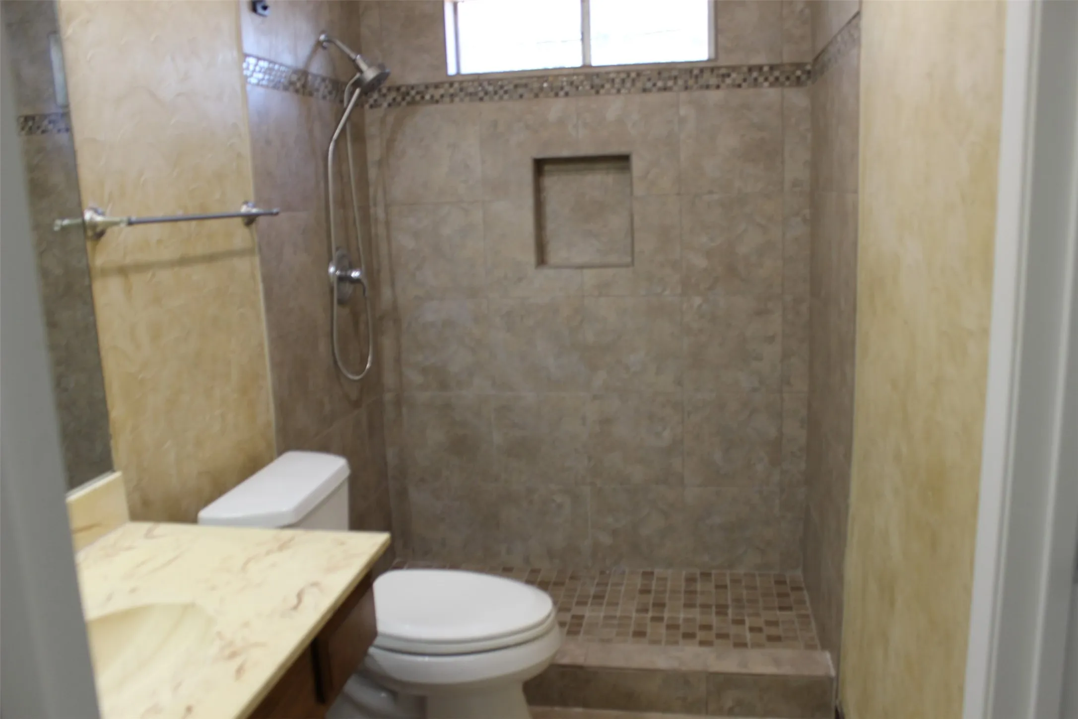 Tiled shower with built-in niche and mosaic-tiled accent band
