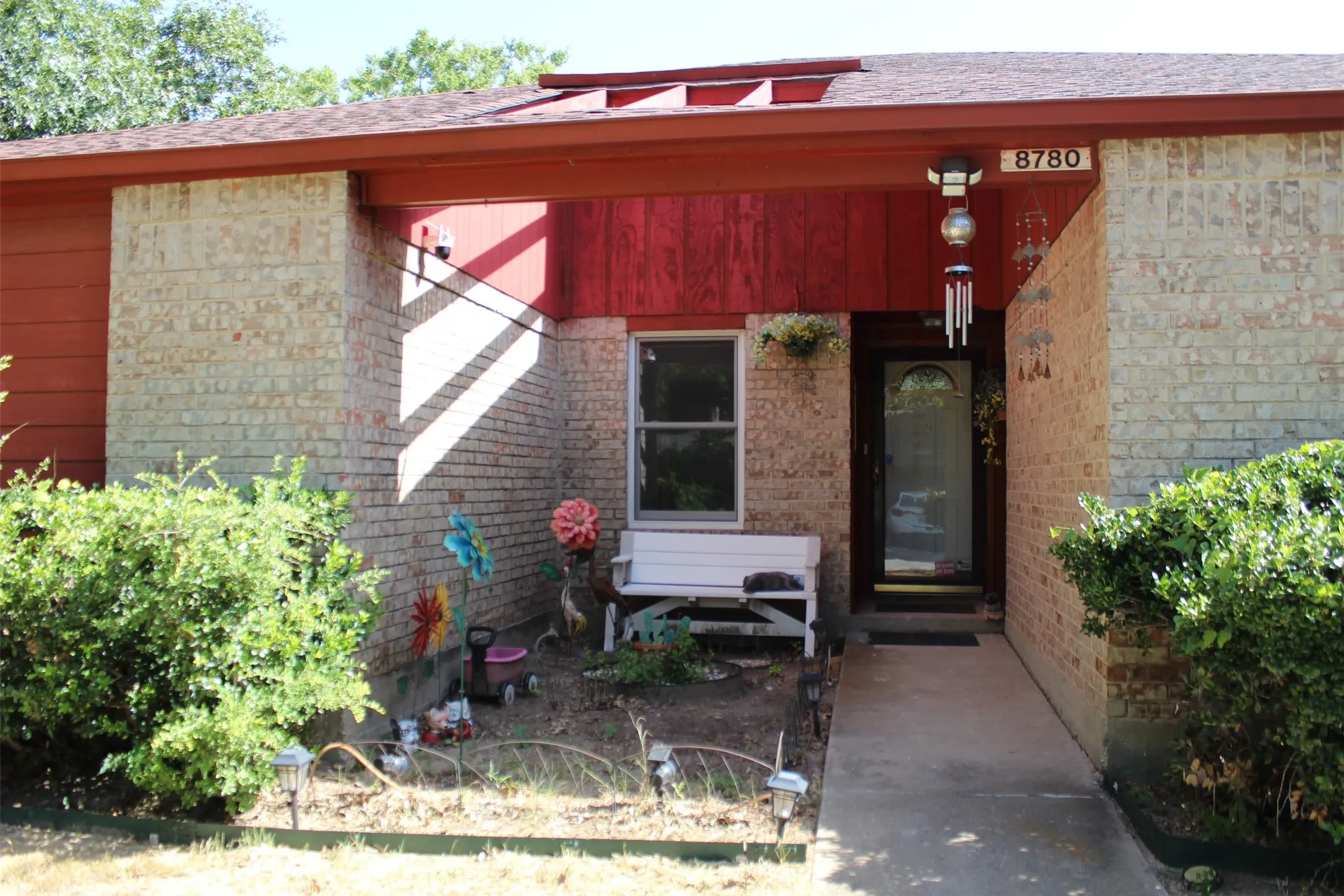 Brick facade with a contrasting red wood-paneled accent, covered entryway, and concrete walkway
