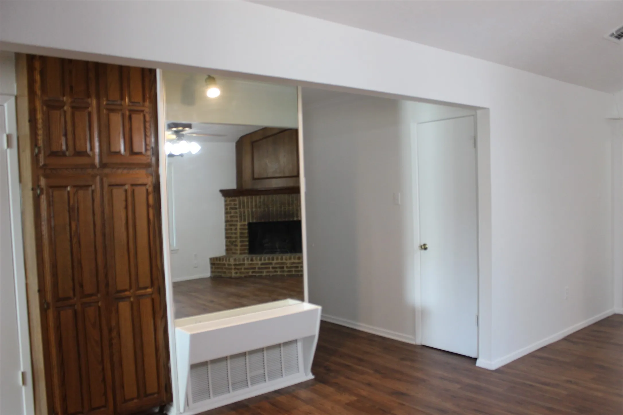 Built-in wood cabinetry, full-length mirror feature, wood-finish flooring, white painted walls, and an interior door