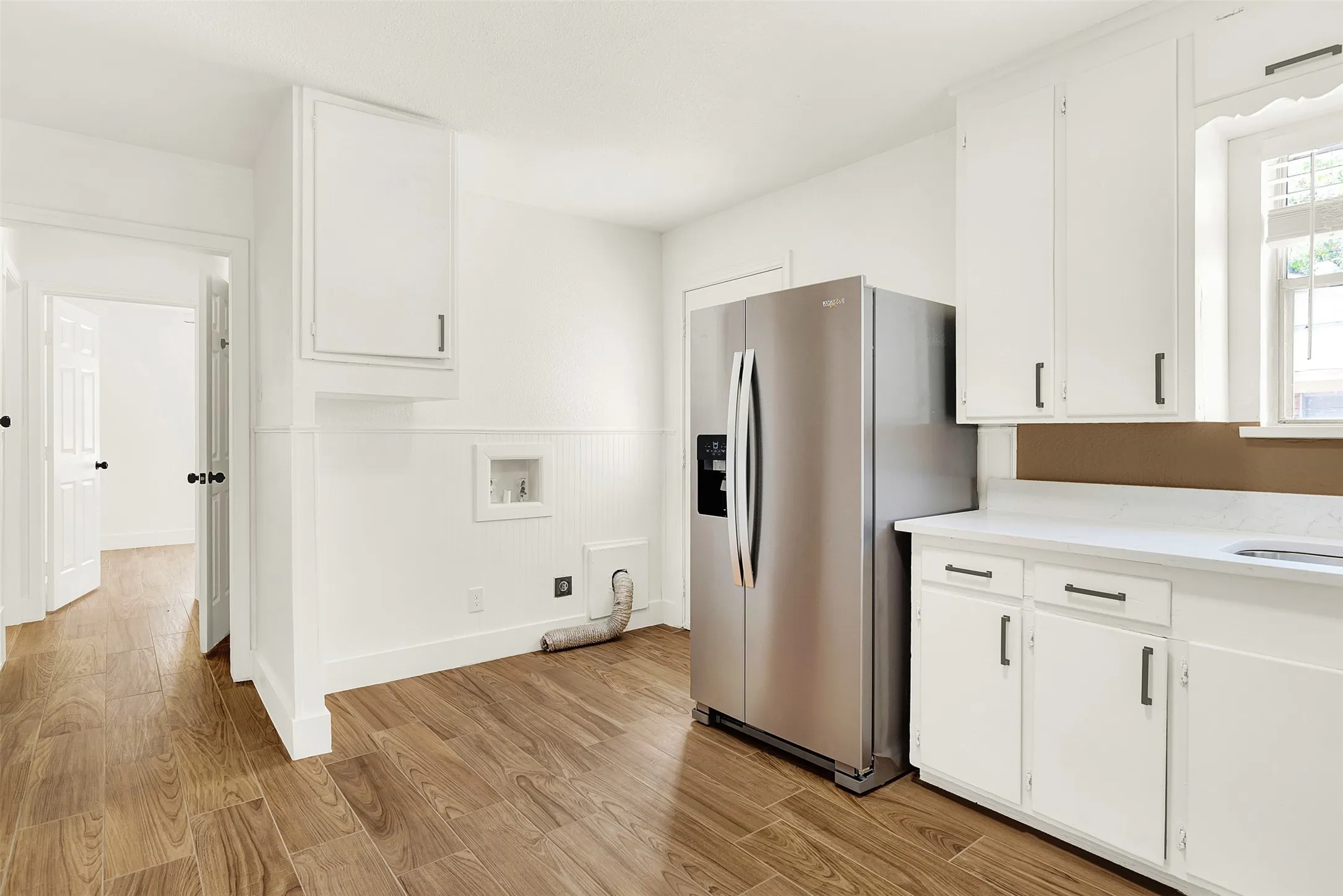 Kitchen featuring light wood-type flooring, stainless steel fridge, and white cabinets