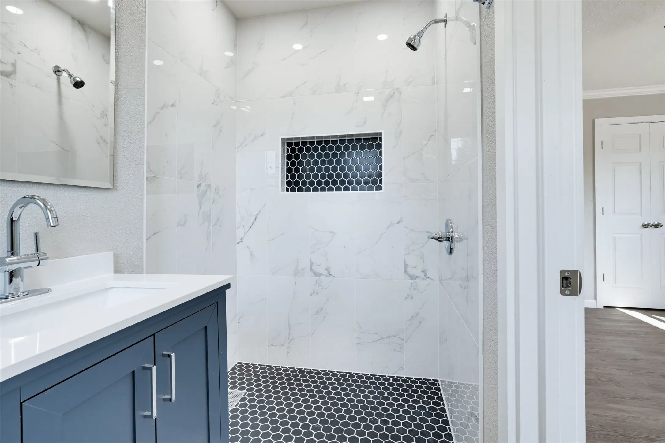 Walk-in shower with large format wall tiles and hex tile flooring