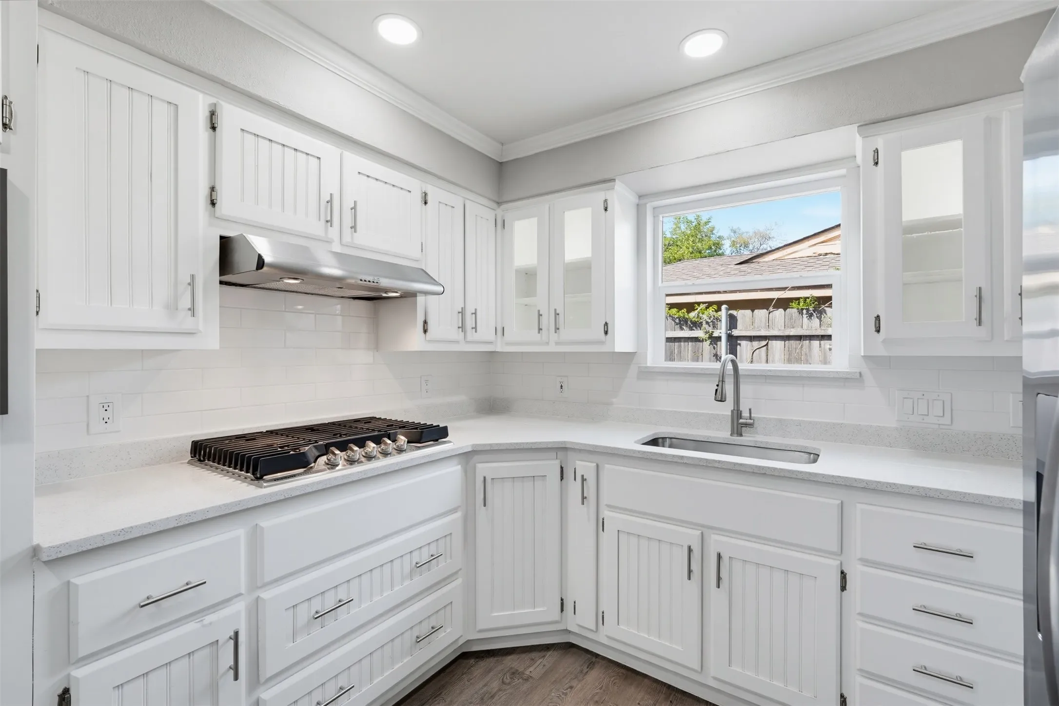 White cabinetry with beadboard paneling, light-toned countertops, and a white subway tile backsplash