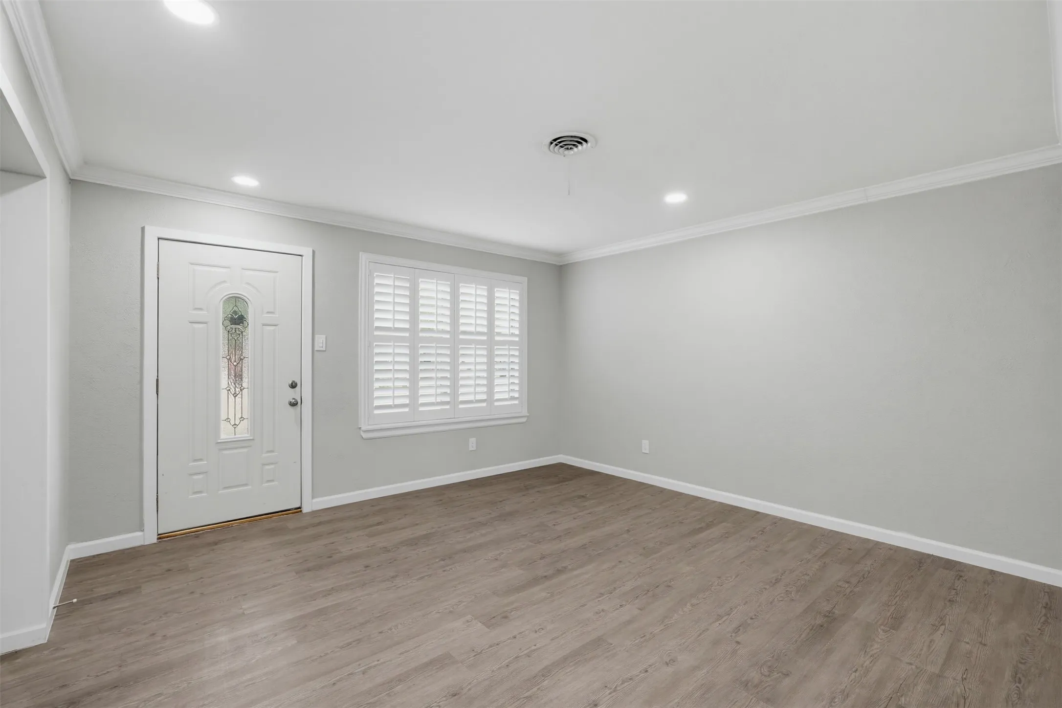 Wood-finish flooring, recessed ceiling lighting, crown molding, and white plantation shutters