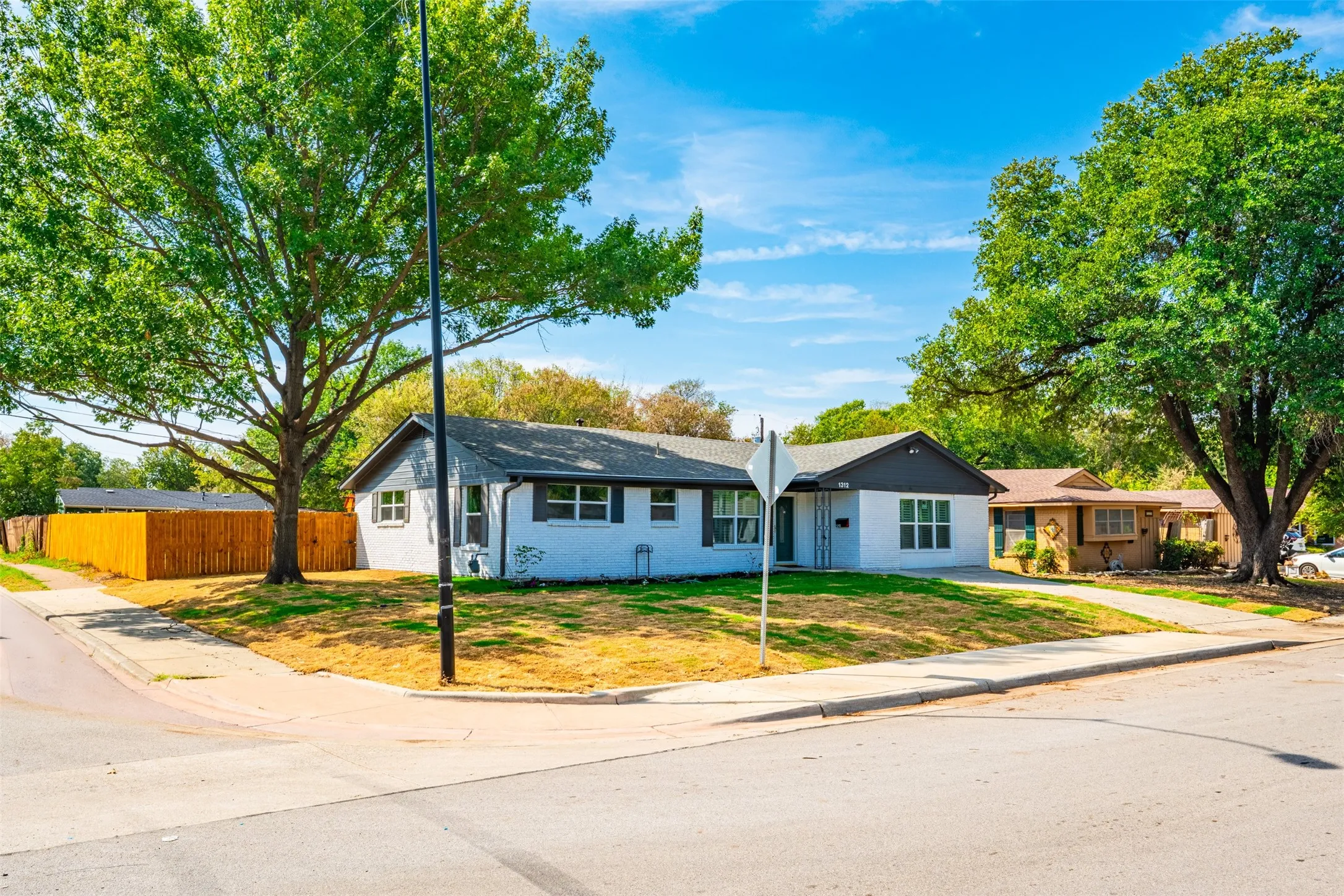 Single-story residence with a white exterior finish and dark trim, featuring a corner lot location