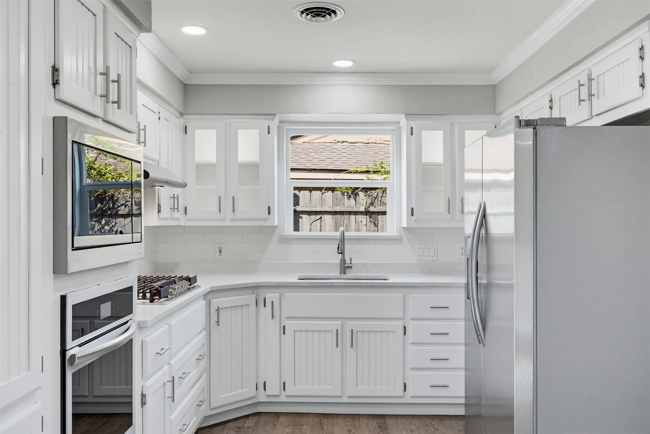 White cabinetry with brushed nickel hardware, stainless steel appliances, and a built-in microwave