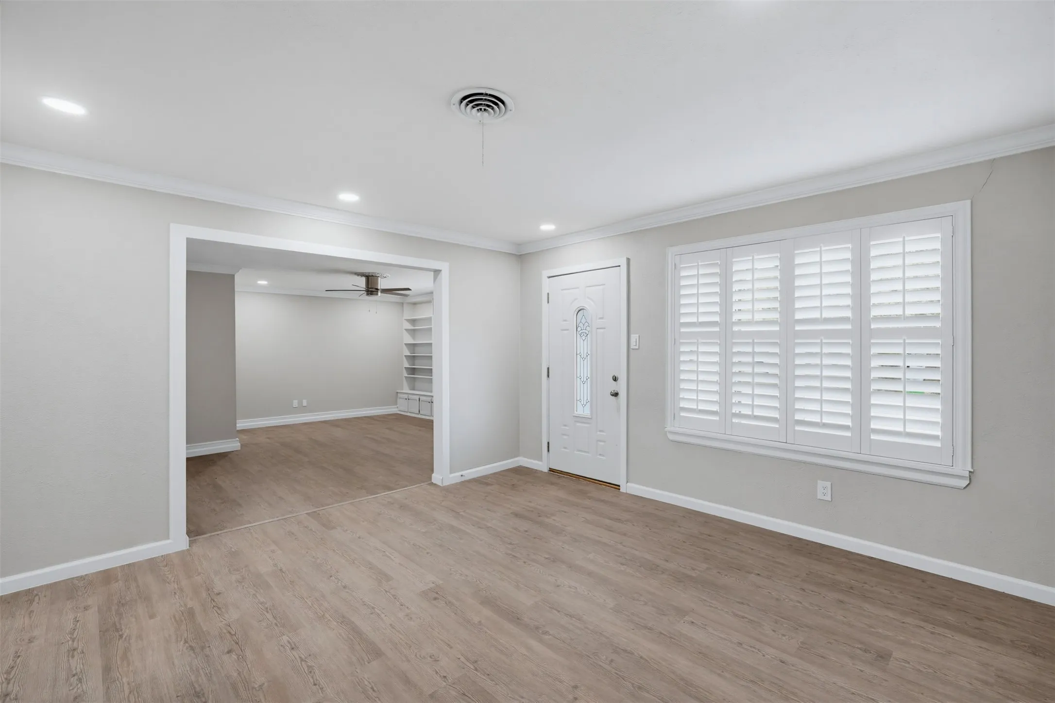 Wood-finish flooring throughout, recessed lighting, and a white entry door with decorative glass inlay