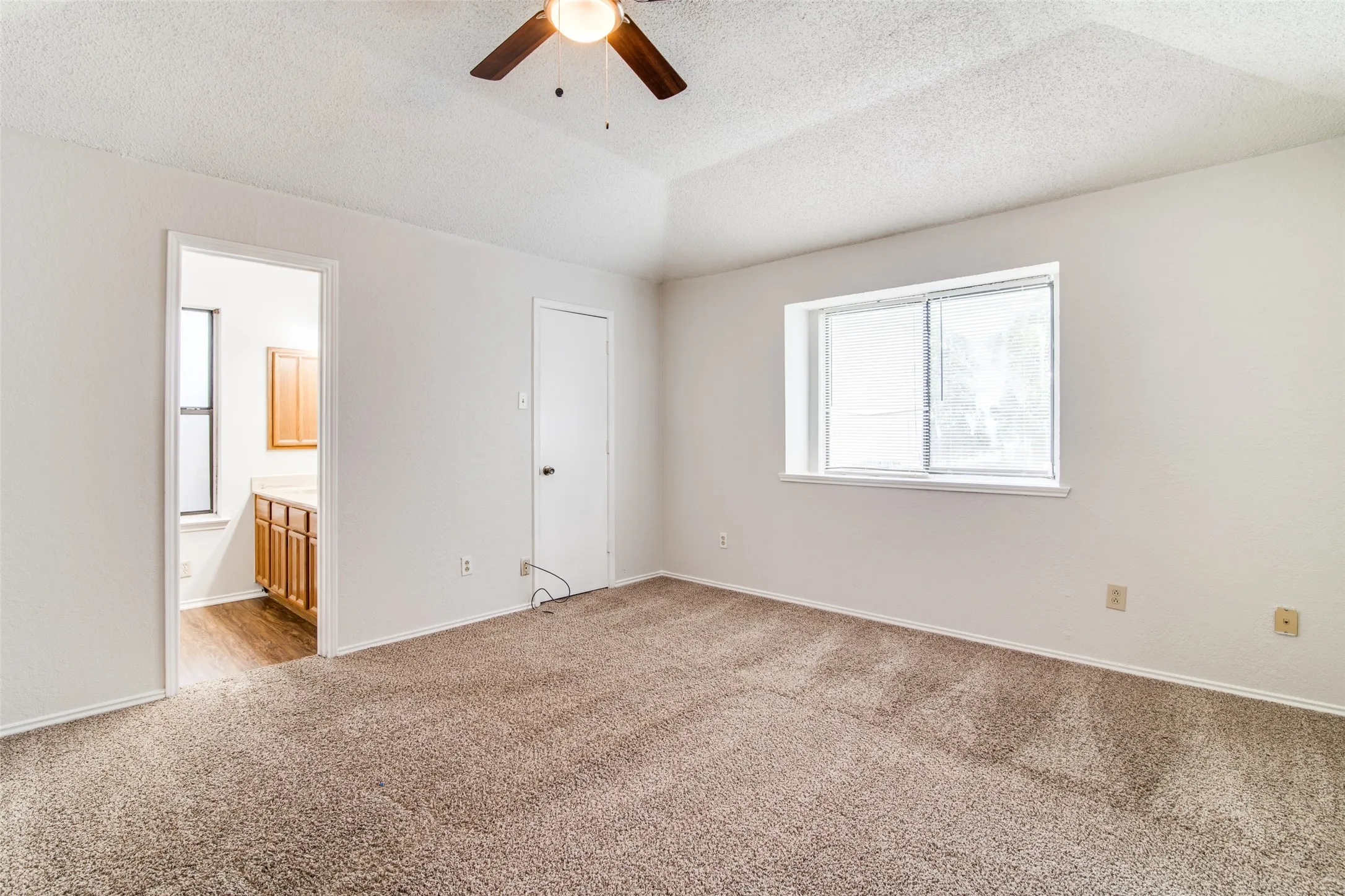 Vaulted ceiling with a ceiling fan, carpeted flooring, and a sliding window