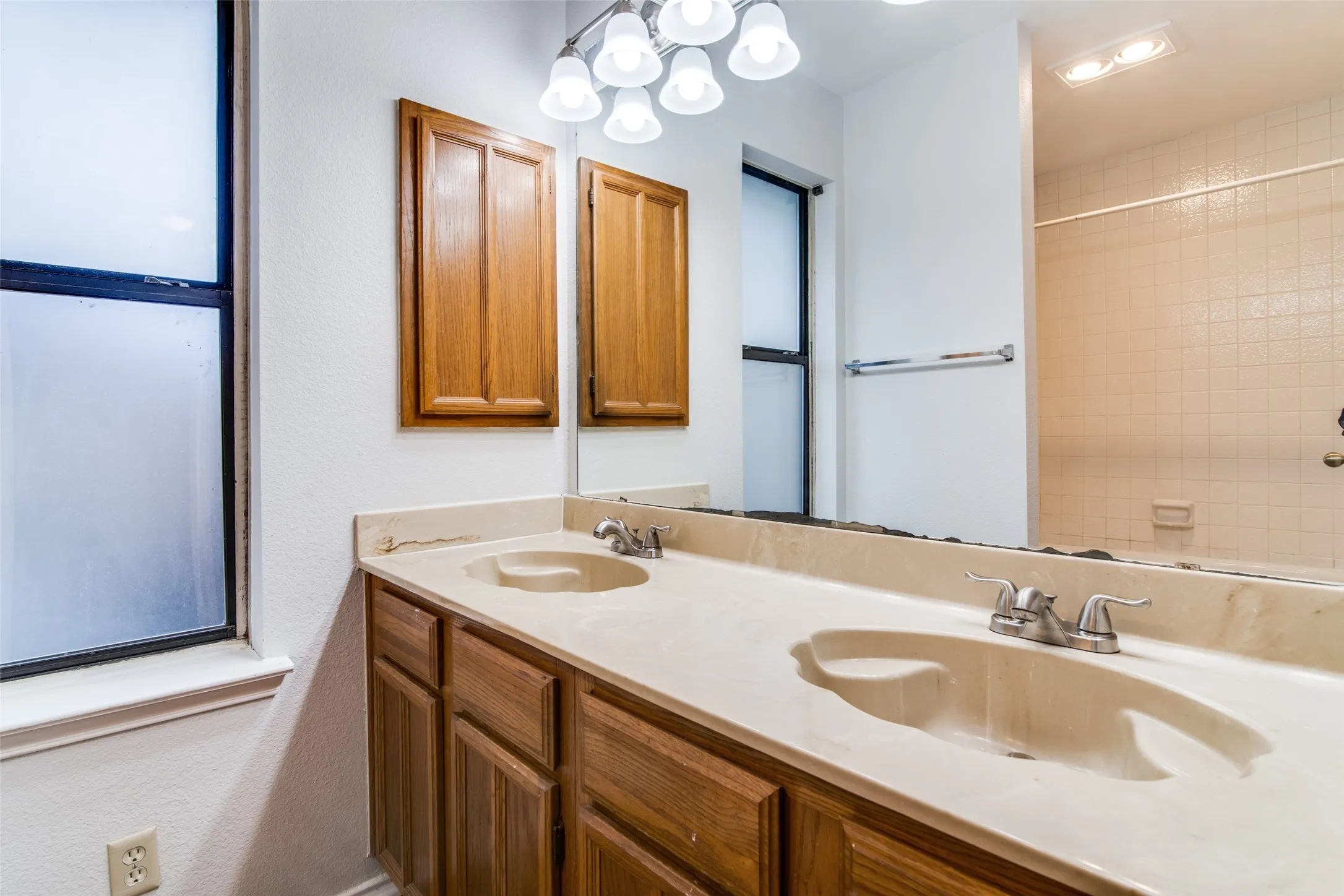 Double vanity with integrated sinks, wood-finish cabinetry, and a full-width mirror