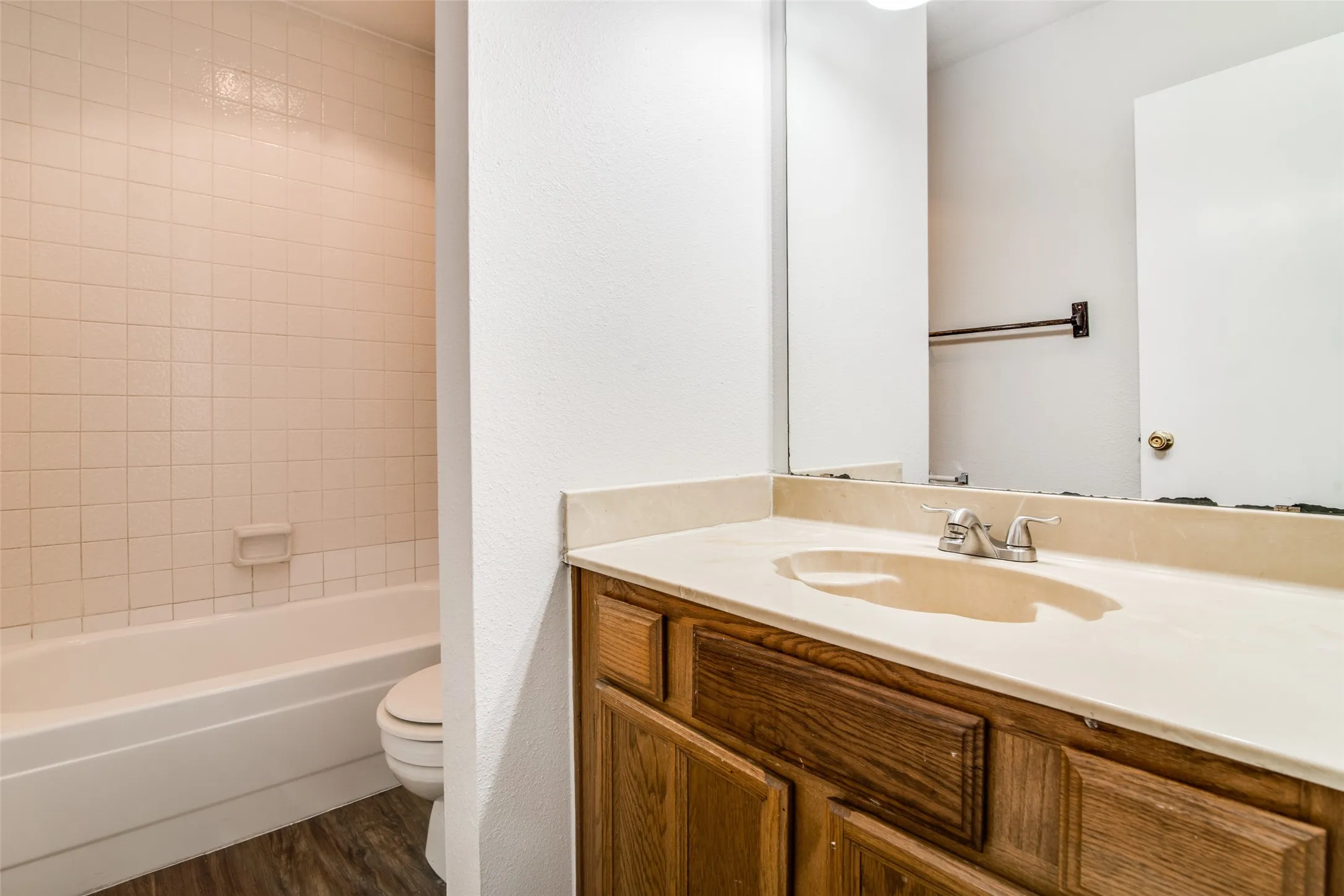 Bathroom featuring a built-in vanity with wood-finish cabinetry, integrated sink, and an expansive wall mirror