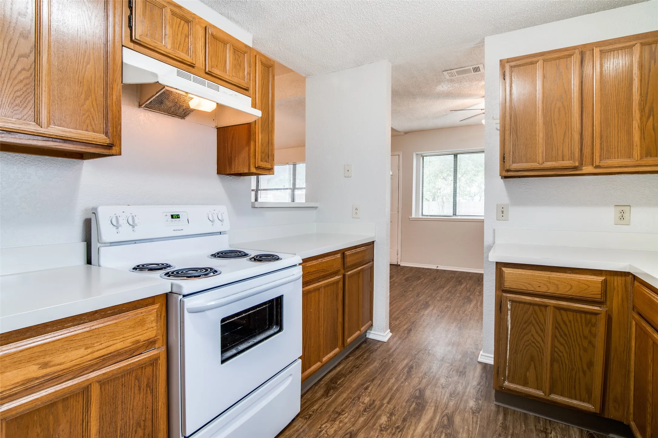 Kitchen featuring wood-finish cabinetry, white countertops, a white electric range, and wood-finish flooring