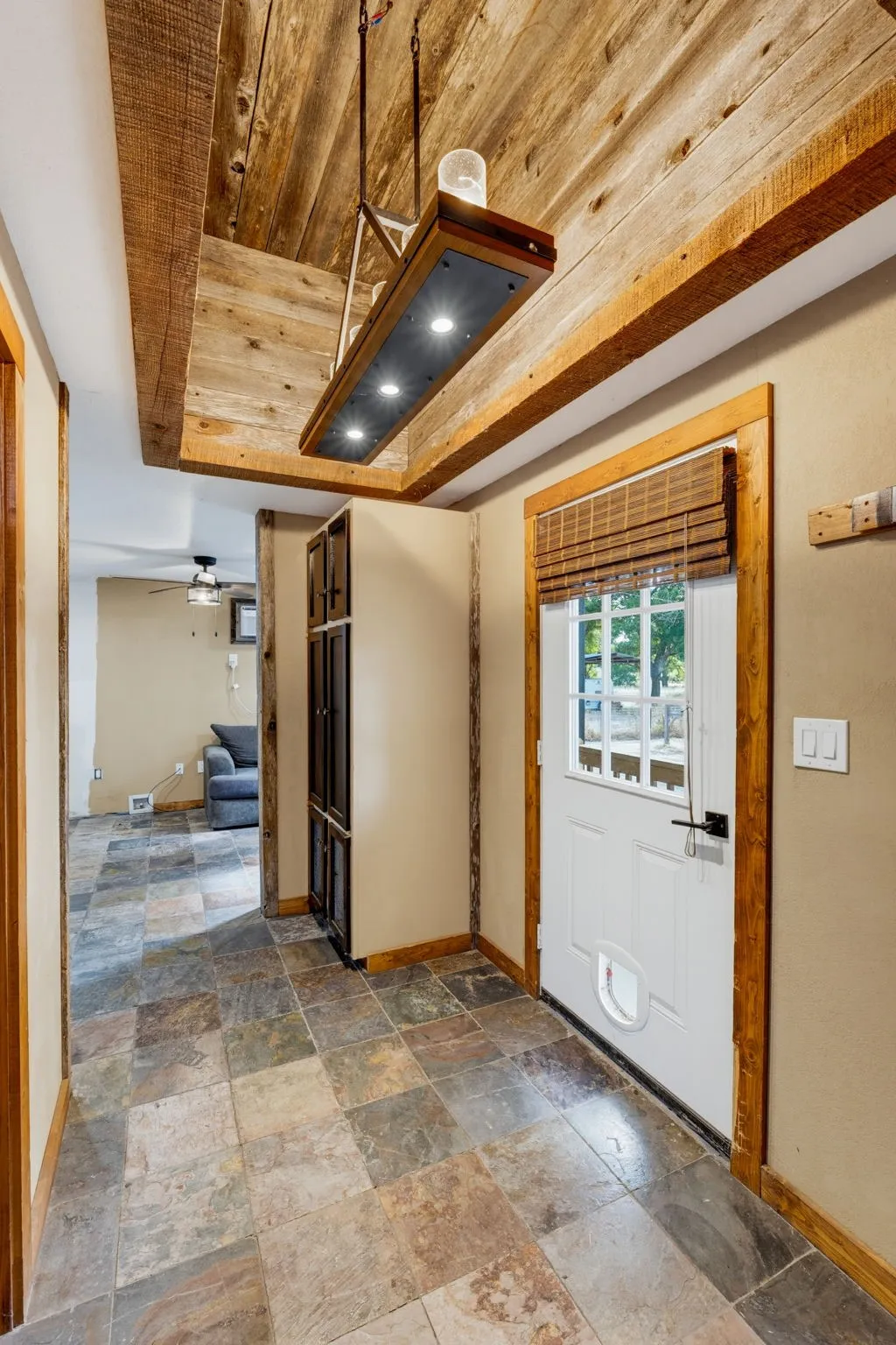Exposed wood-beam ceiling with wood plank detailing, multi-tone tile flooring, and custom wood trim around doorways