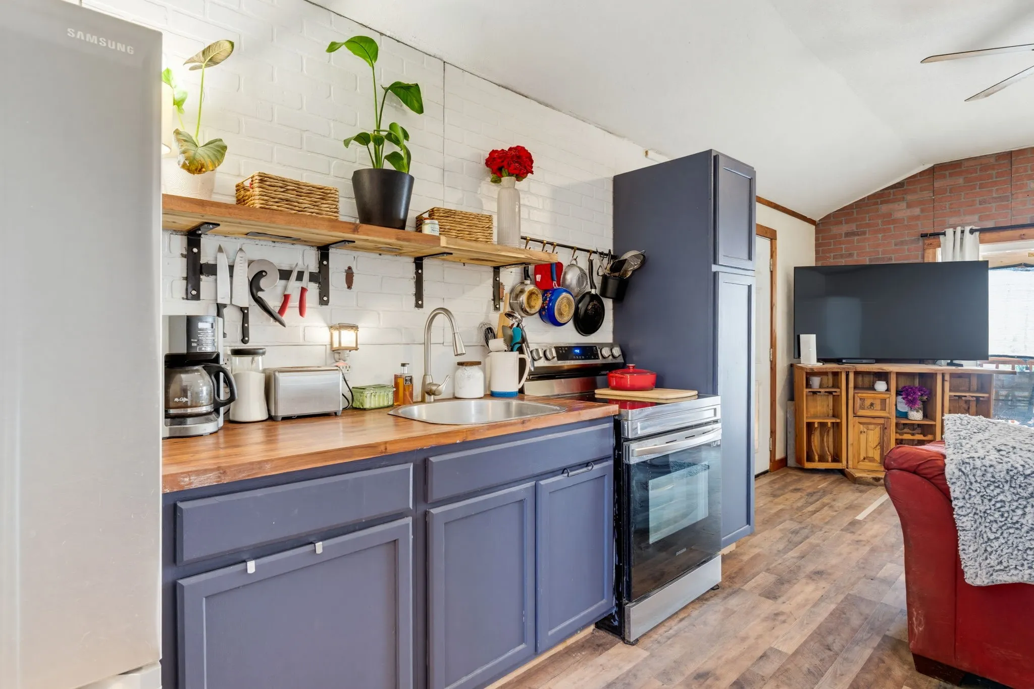 Kitchen featuring wood-finish countertops, blue cabinetry, stainless steel oven, and open shelving