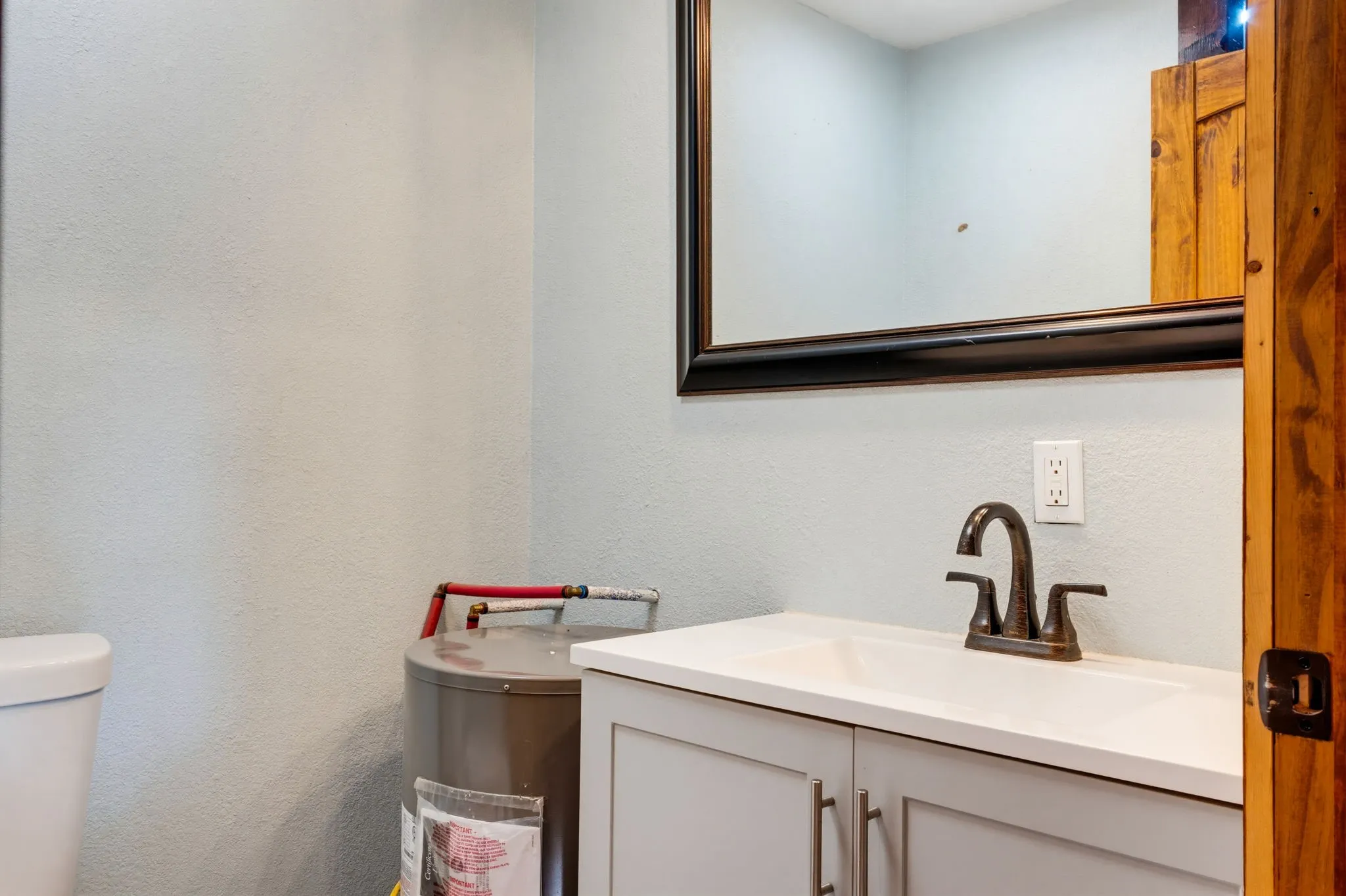 White vanity with integrated sink, dark bronze-finish faucet, and framed wall mirror