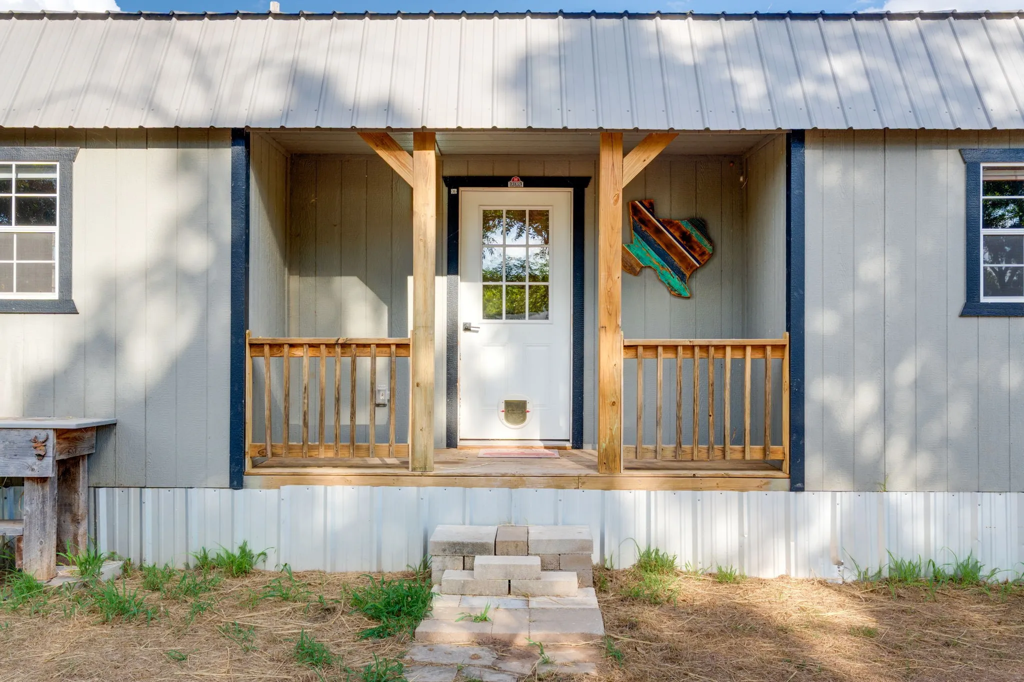 Front entry with a white paneled door, wood-frame windows, and a metal roof