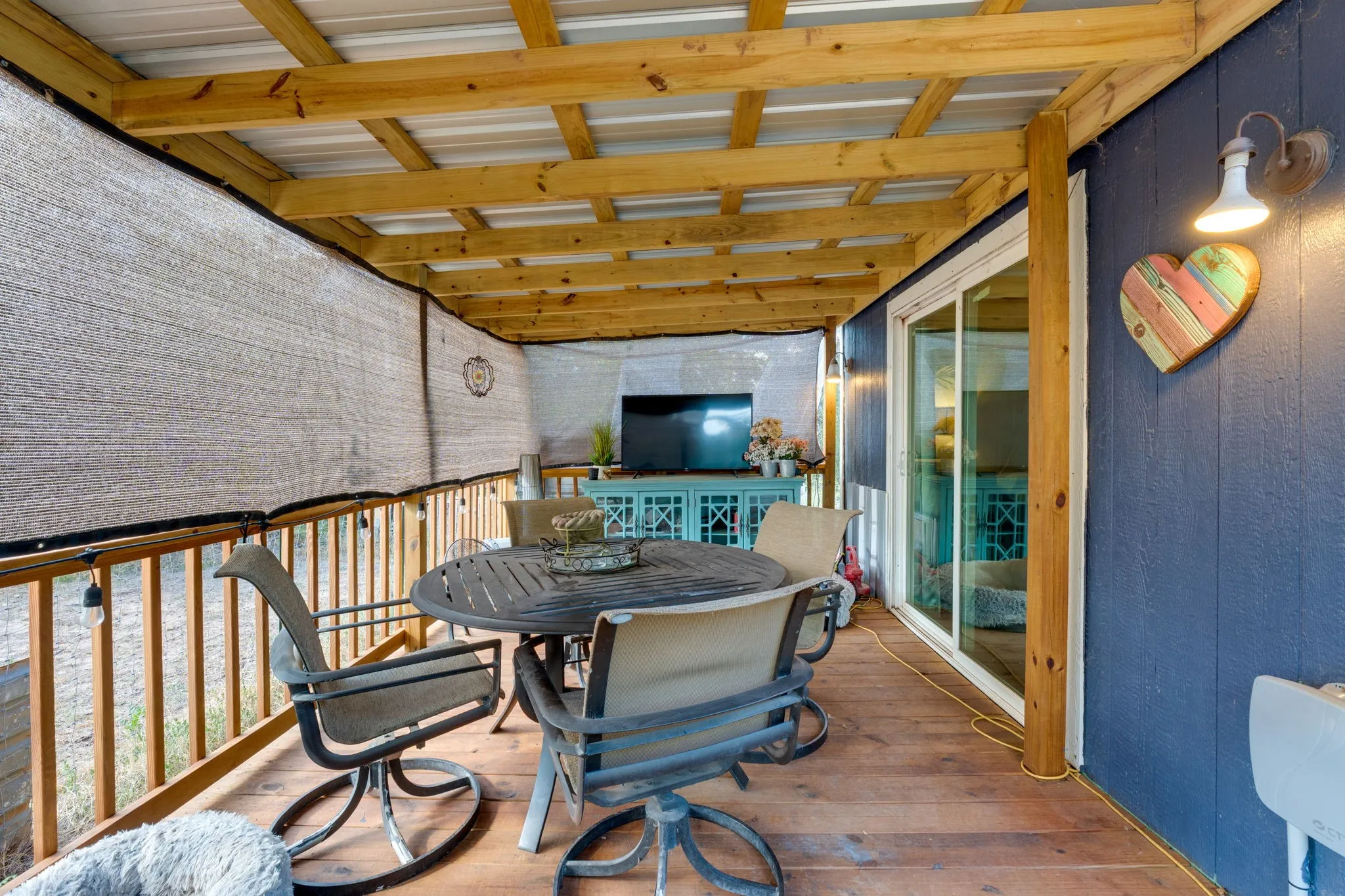 Covered porch with exposed wood beams, wood-finish flooring, and a sliding glass door