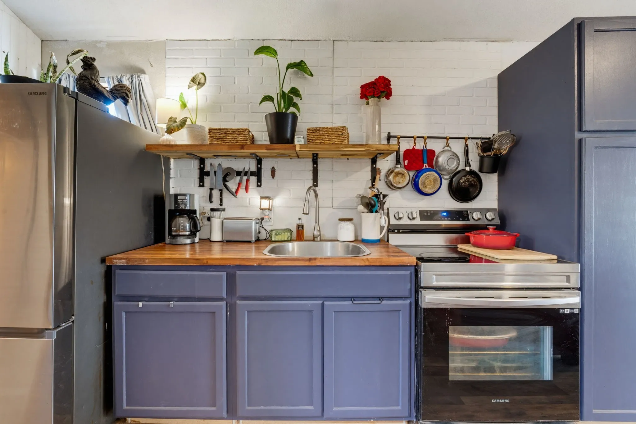 Compact kitchen featuring a stainless steel refrigerator, built-in oven, and a double basin sink