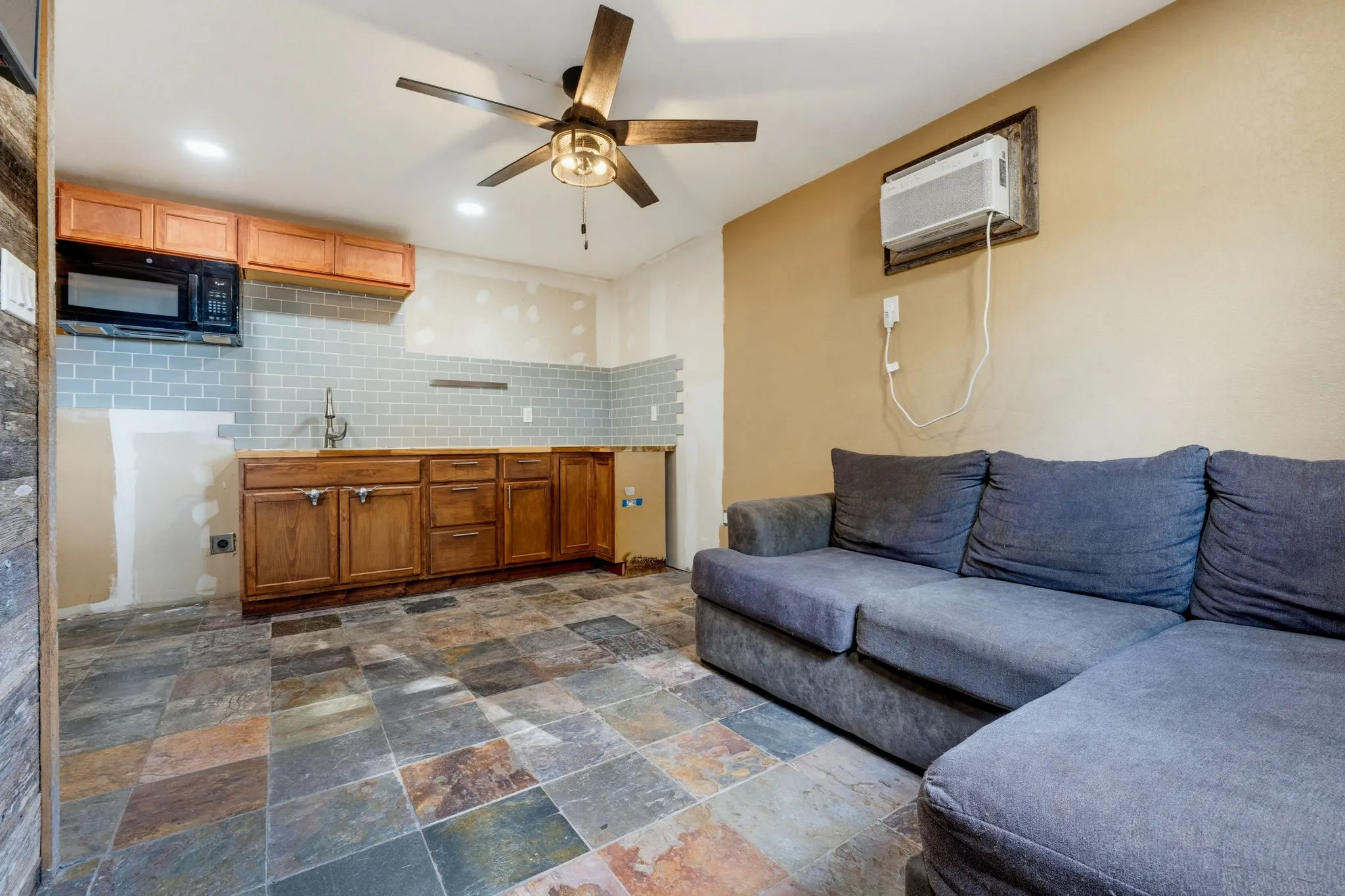 Kitchenette with wood cabinetry, subway tile backsplash, and built-in microwave