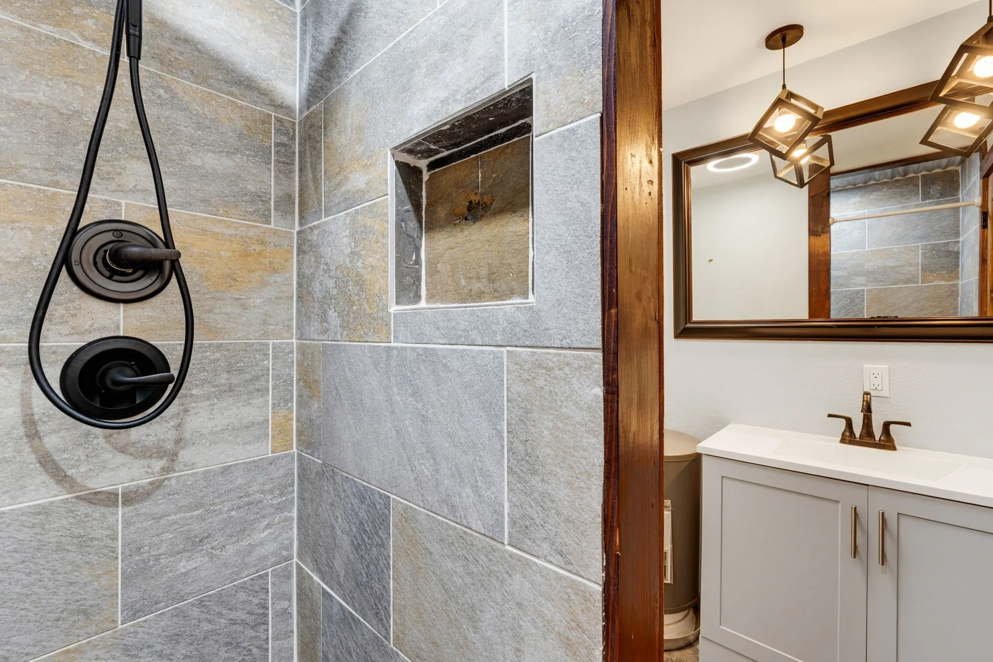 Textured shower tile with built-in niche, featuring a matte black shower system