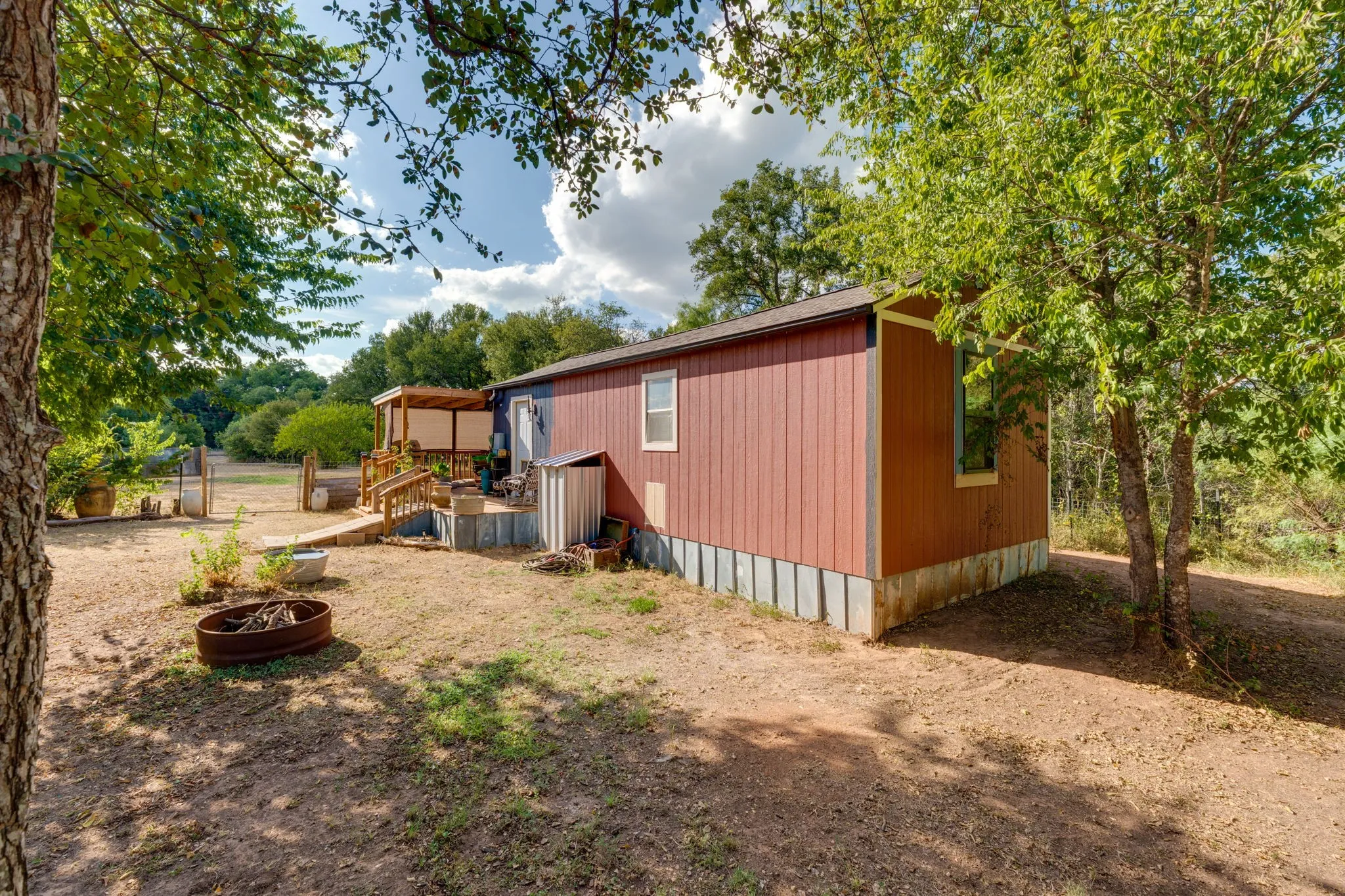 Exterior featuring red vertical siding, white window trim, and an expansive wooden deck with a pergola