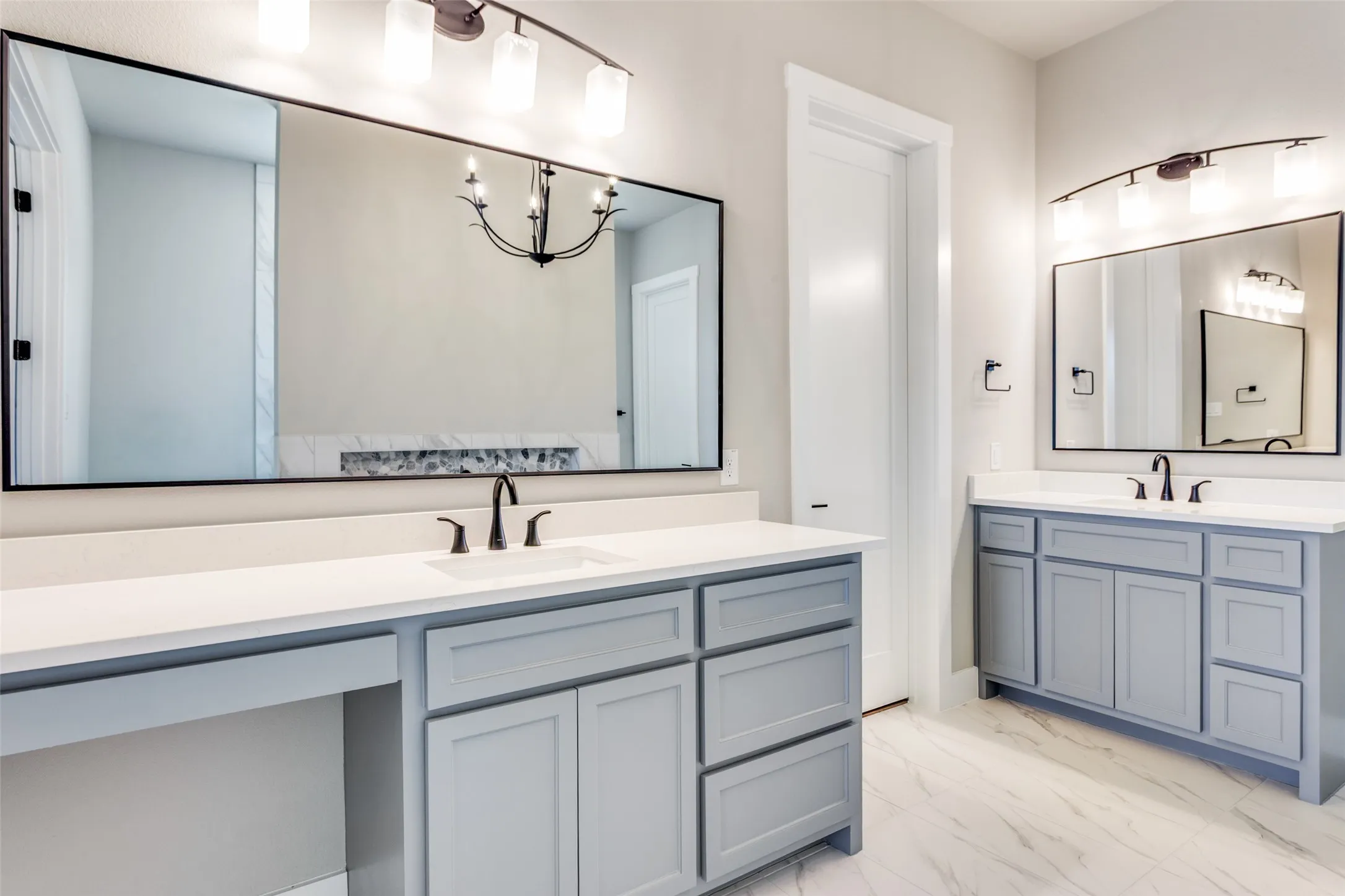 Dual vanities with matte black fixtures, light gray cabinetry, white countertops, and expansive mirrors