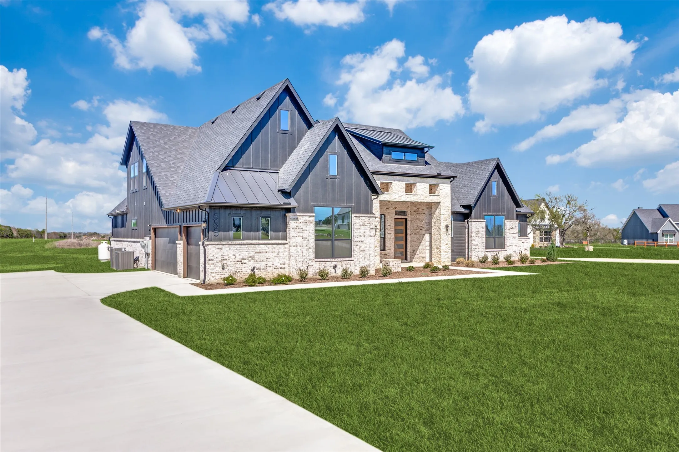 Modern farmhouse exterior featuring a light brick facade and dark vertical siding