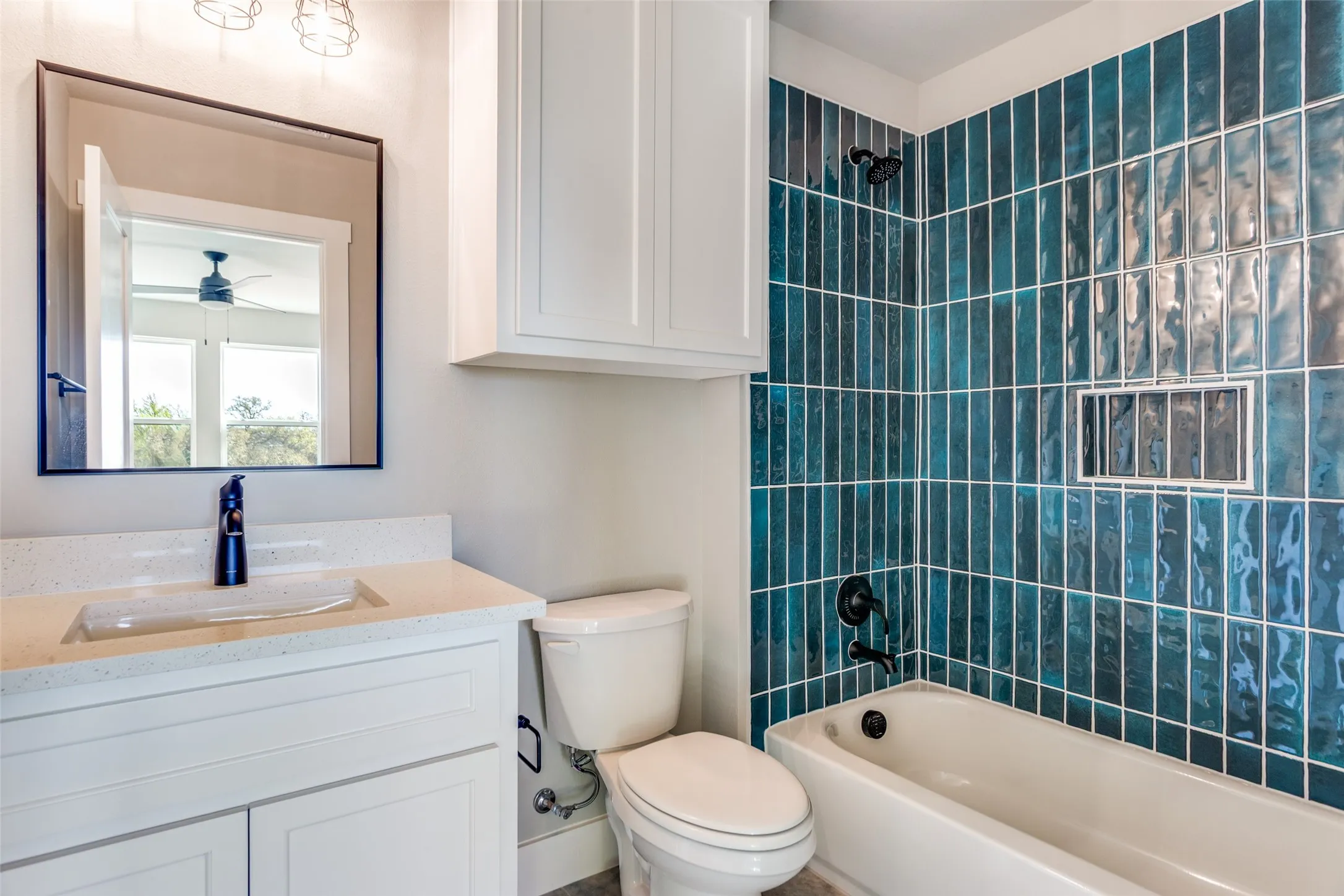 White vanity with integrated sink and dark-toned faucet, complemented by a framed rectangular mirror