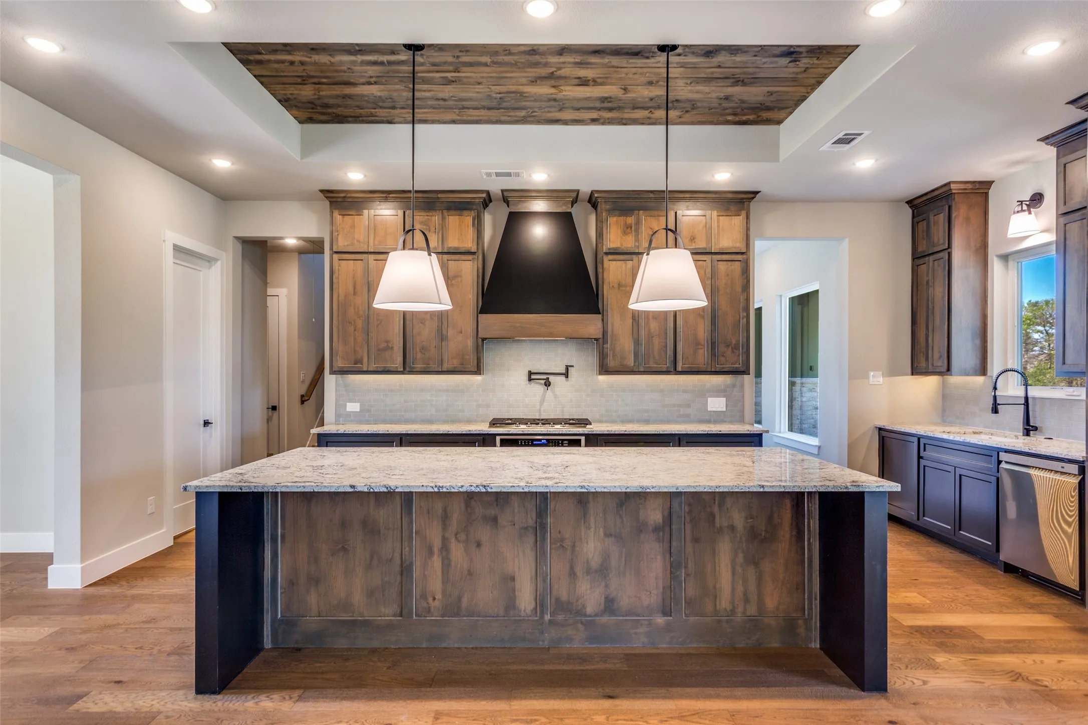 Kitchen featuring a wood-panel accent ceiling, recessed lighting, and a large central island with a light-toned countertop