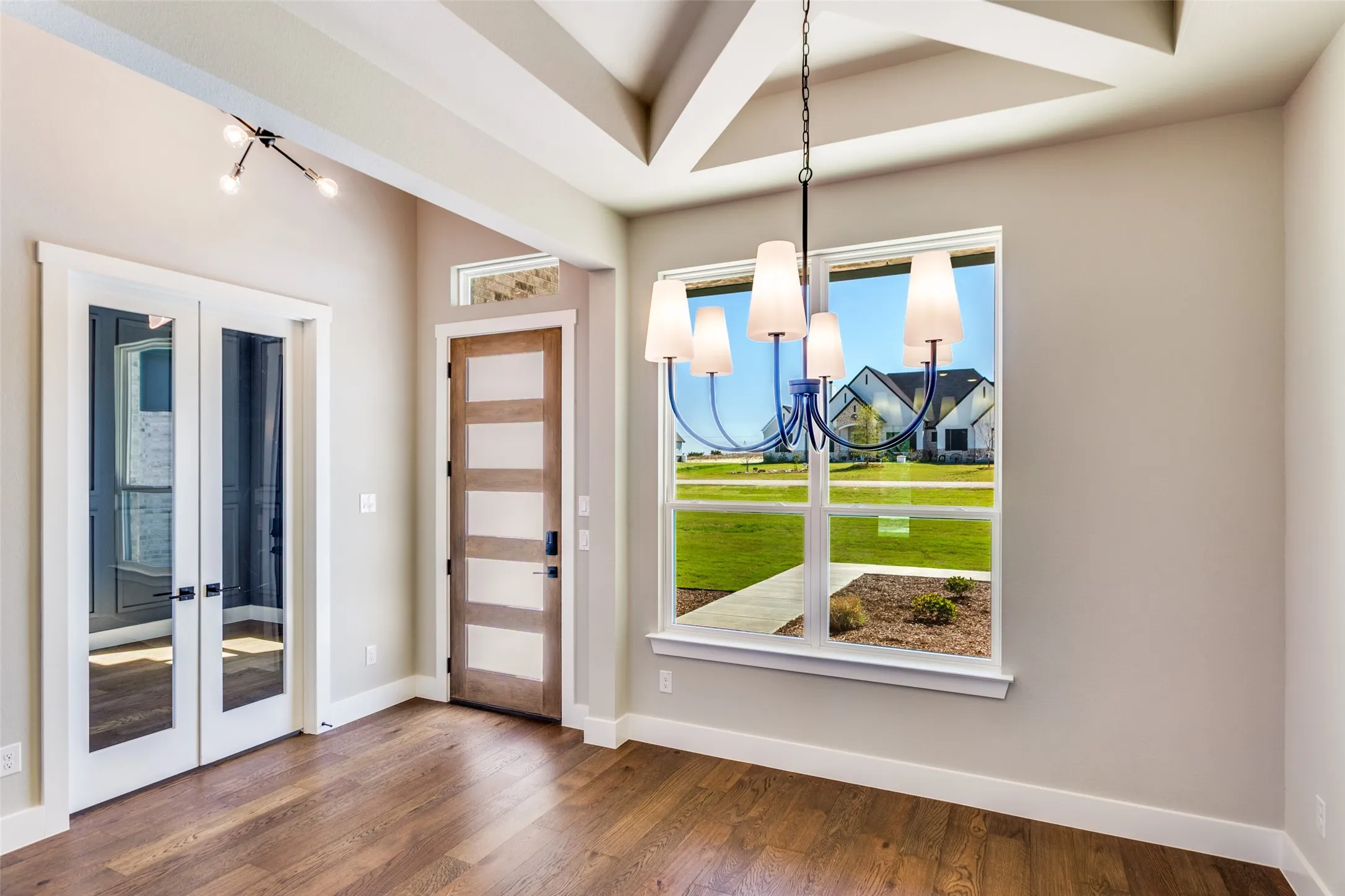 Tray ceiling with recessed lighting, wood-finish flooring, full-light French doors, contemporary chandelier, and a five-panel wood-finish entry door