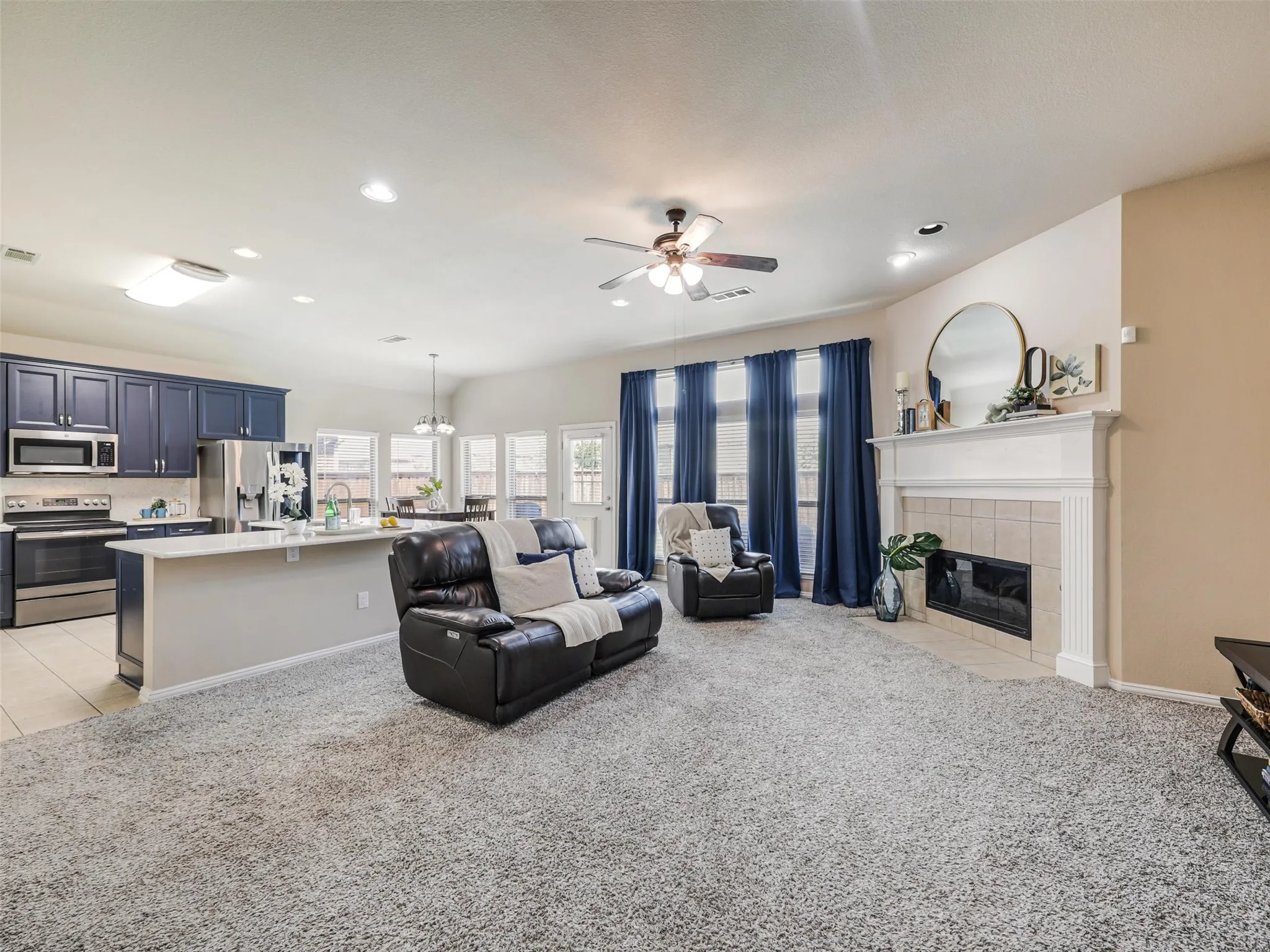 Open living area features a fireplace with a decorative mantel, tall windows, and easy connection to the kitchen for everyday living and entertaining.