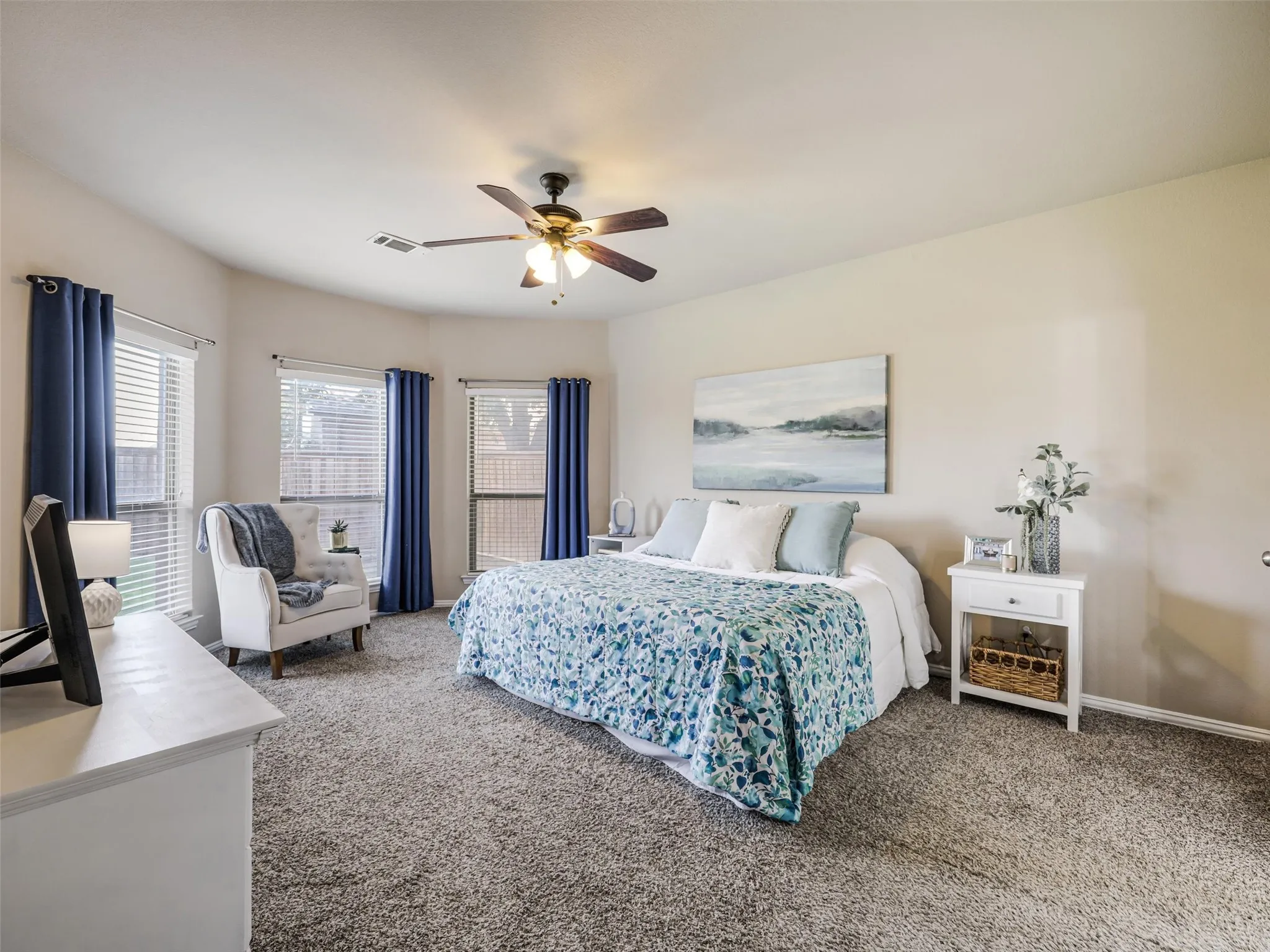 Spacious primary bedroom offers abundant natural light, a ceiling fan, and room for a comfortable reading nook.