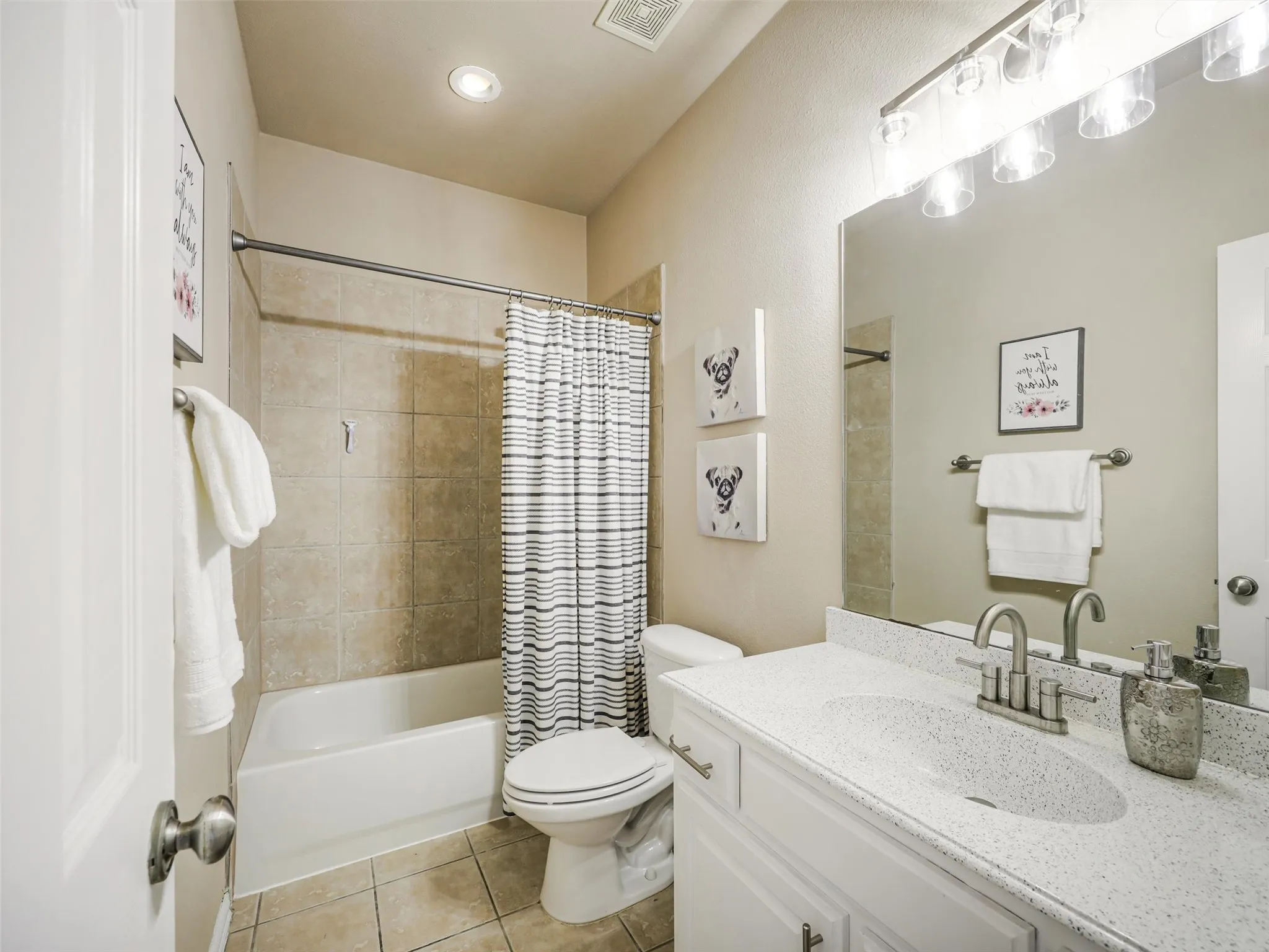 Full bathroom offers a white vanity, generous counter space, and a tub-shower combination with tile surround.