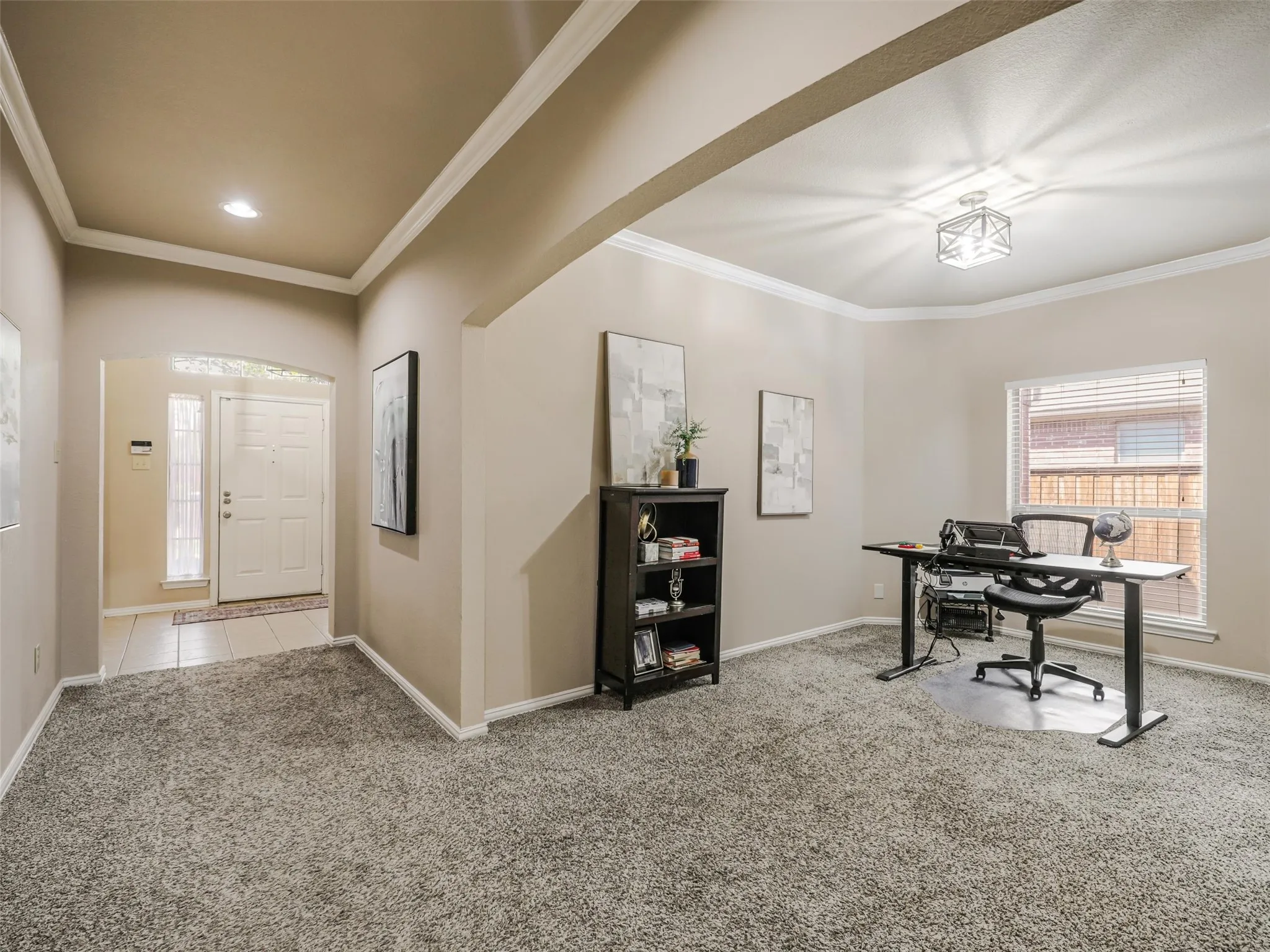 Versatile front room, currently used as a home office, features crown molding, natural light, and a wide opening to the entry hallway.