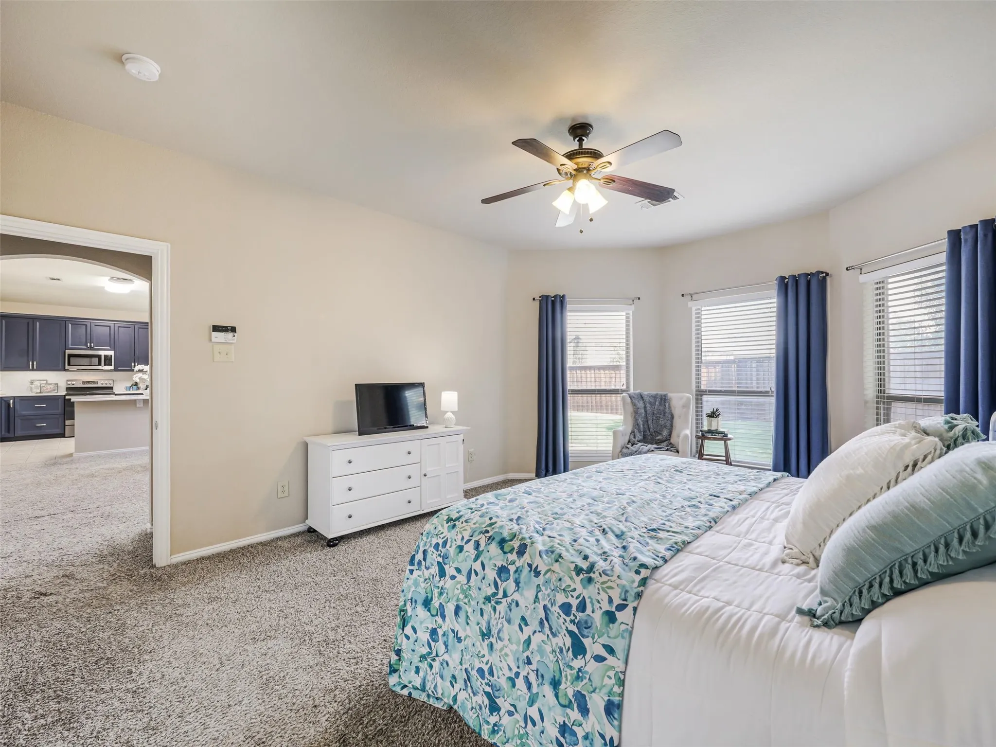 Multiple windows brighten the generously sized primary bedroom, offering ample space for bedroom furnishings and a sitting area.