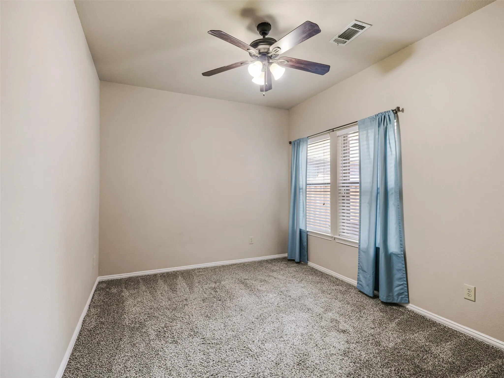 Versatile secondary bedroom with neutral finishes, carpeting, and a ceiling fan offers space for guests, work, or hobbies.